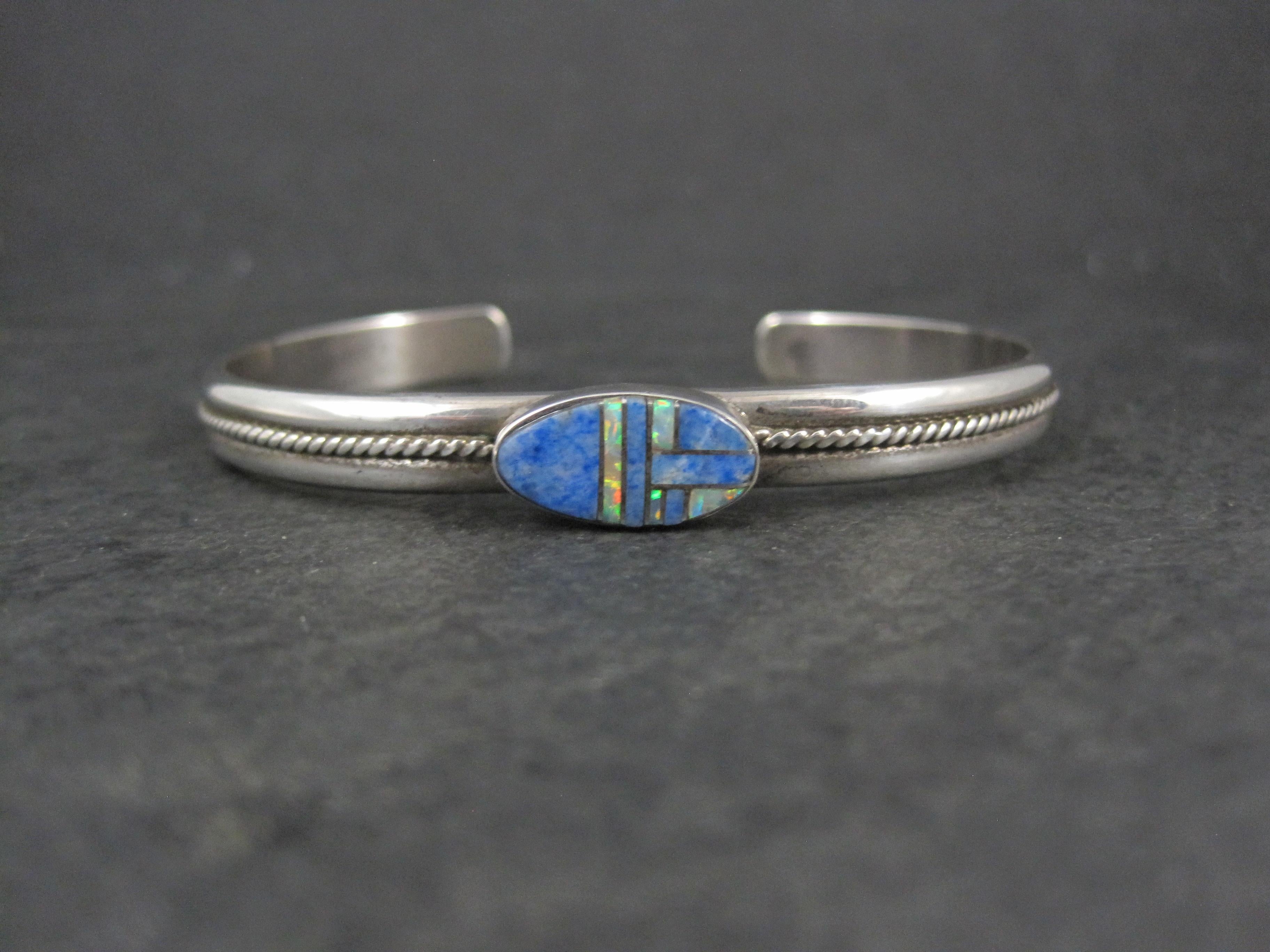 This gorgeous vintage cuff bracelet is new old stock.
It features stunning denim lapis and opal inlay.

The face of this bracelet measures 5/16 of an inch wide. The band measures 1/4 of an inch wide. 
The inner circumference  measures 6 1/2 inches