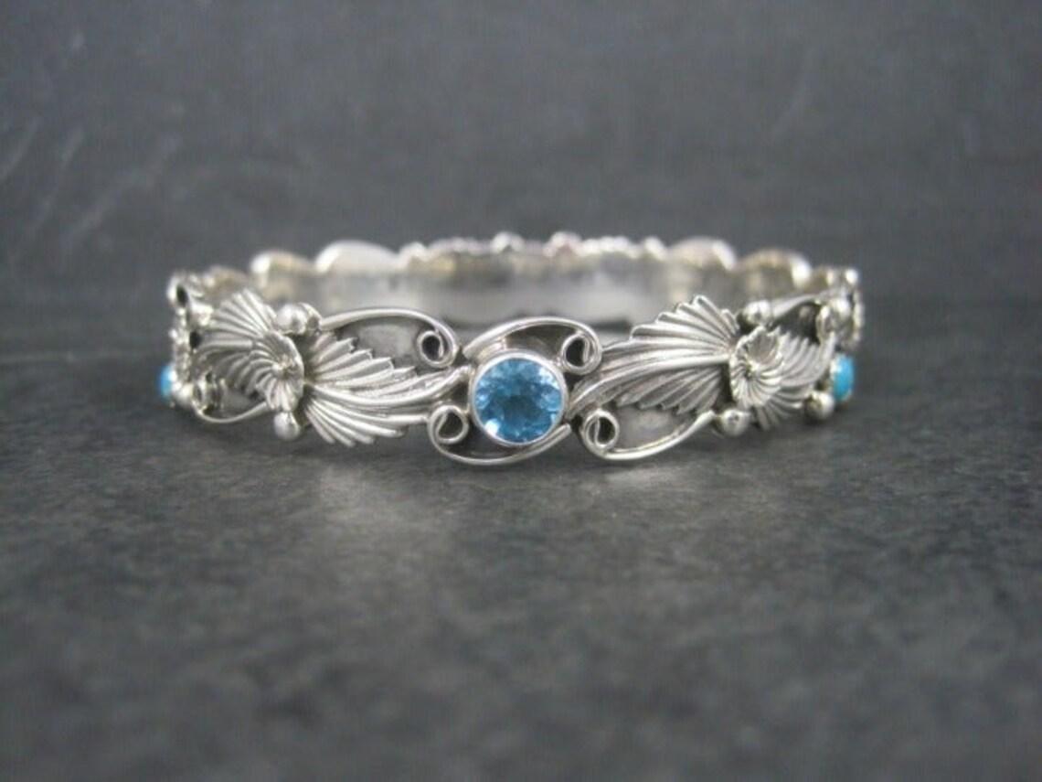 This gorgeous Southwestern bangle bracelet is sterling silver.
It features 3 round 6mm topaz and 3 snake eye cut 4mm turquoise gemstones.

Measurements: 12mm wide - Inner circumference of 7 1/2 inches - Inner diameter of 2 1/2 inches
Weight: 26.5
