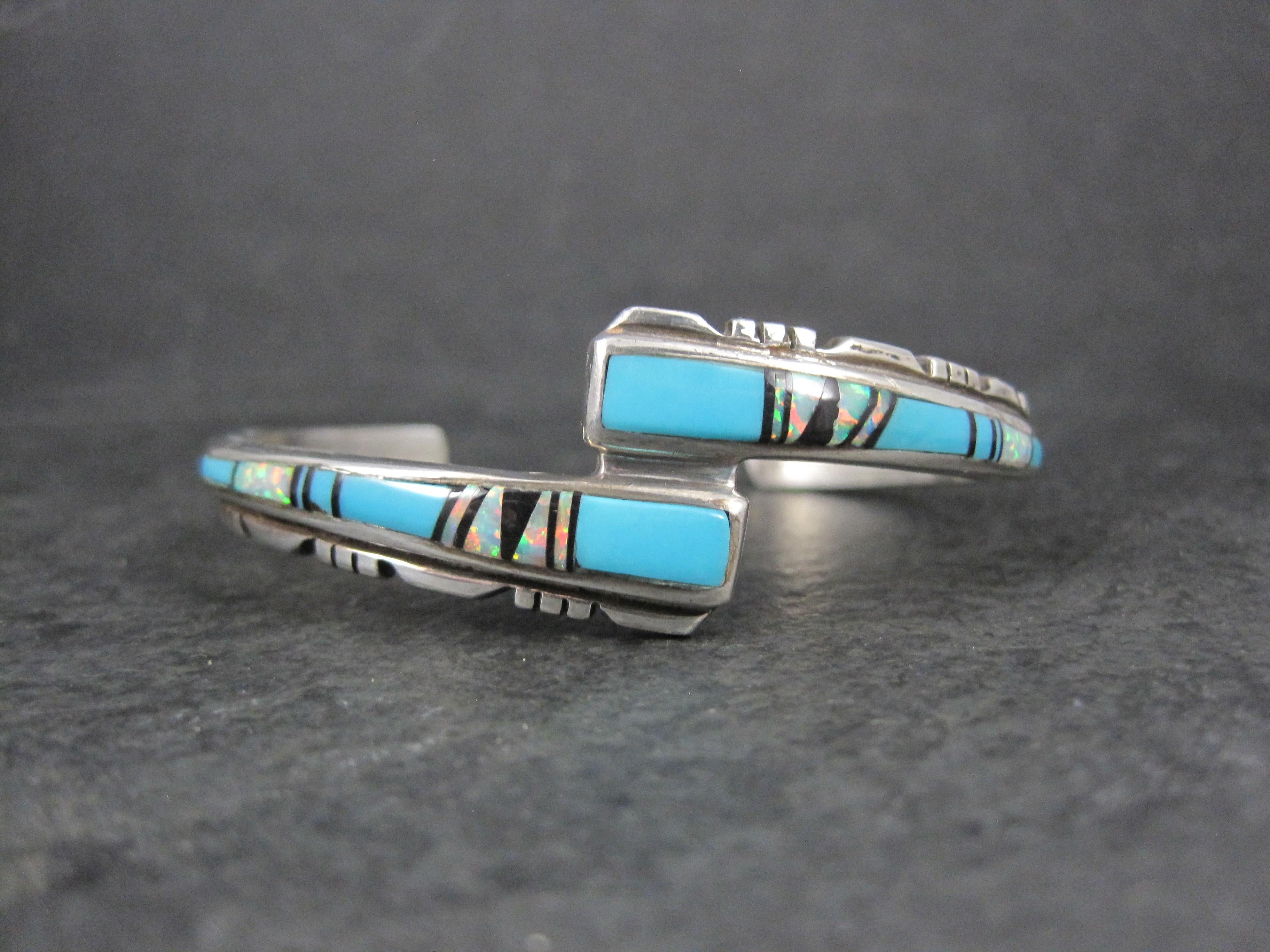 This beautiful, vintage, Southwestern cuff bracelet is sterling silver.
It features a combination of turquoise, opal and jet inlay.

The face of this cuff bracelet is 3/4 of an inch at its widest point.
It has an inner circumference of 5 3/4 inches,