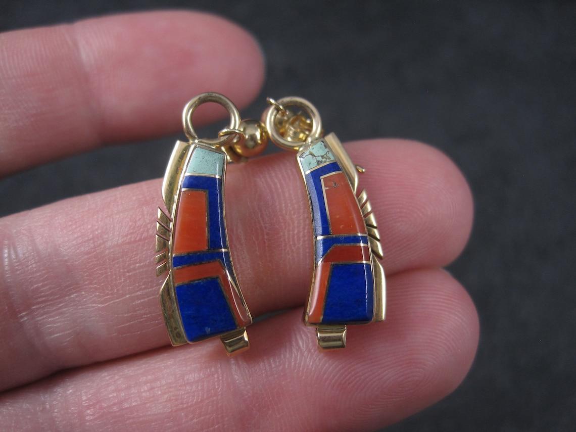These gorgeous, vintage, Southwestern earrings are 14k yellow gold.

They feature inlay in natural turquoise, coral and lapis lazuli.

Measurements: 5/16 of an inch at their widest, 1 1/4 inches long.
Weight: 4.3 grams

Marks: 14K, TD

Condition: