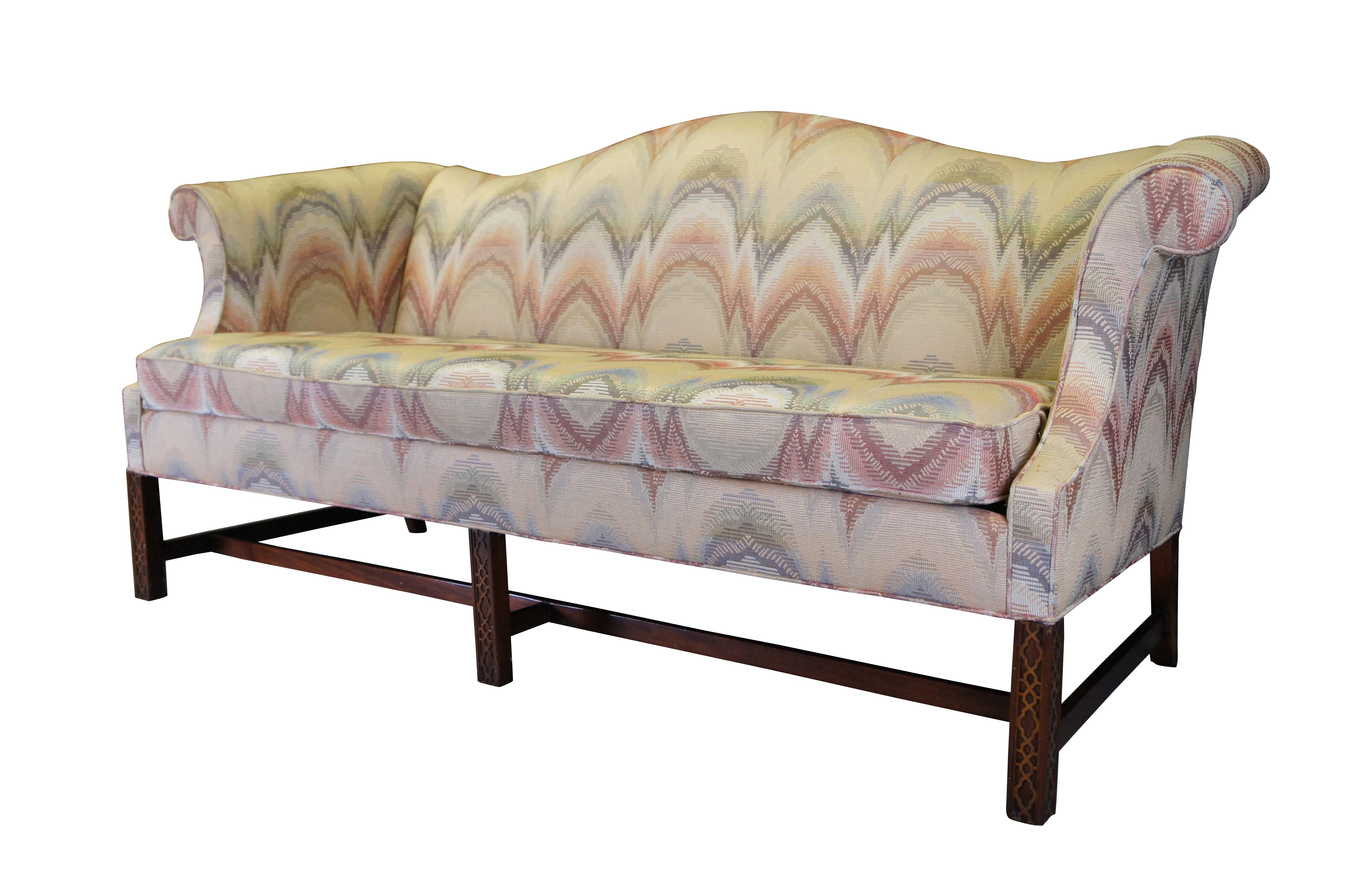 Southwood Chippendale camelback parlor sofa or couch, circa 1980s.  Made of mahogany featuring flame stitch fabric with rolled arms and fretwork legs connected by H stretcher.

Southwood was founded in 1973 specializing in 18th century upholstery