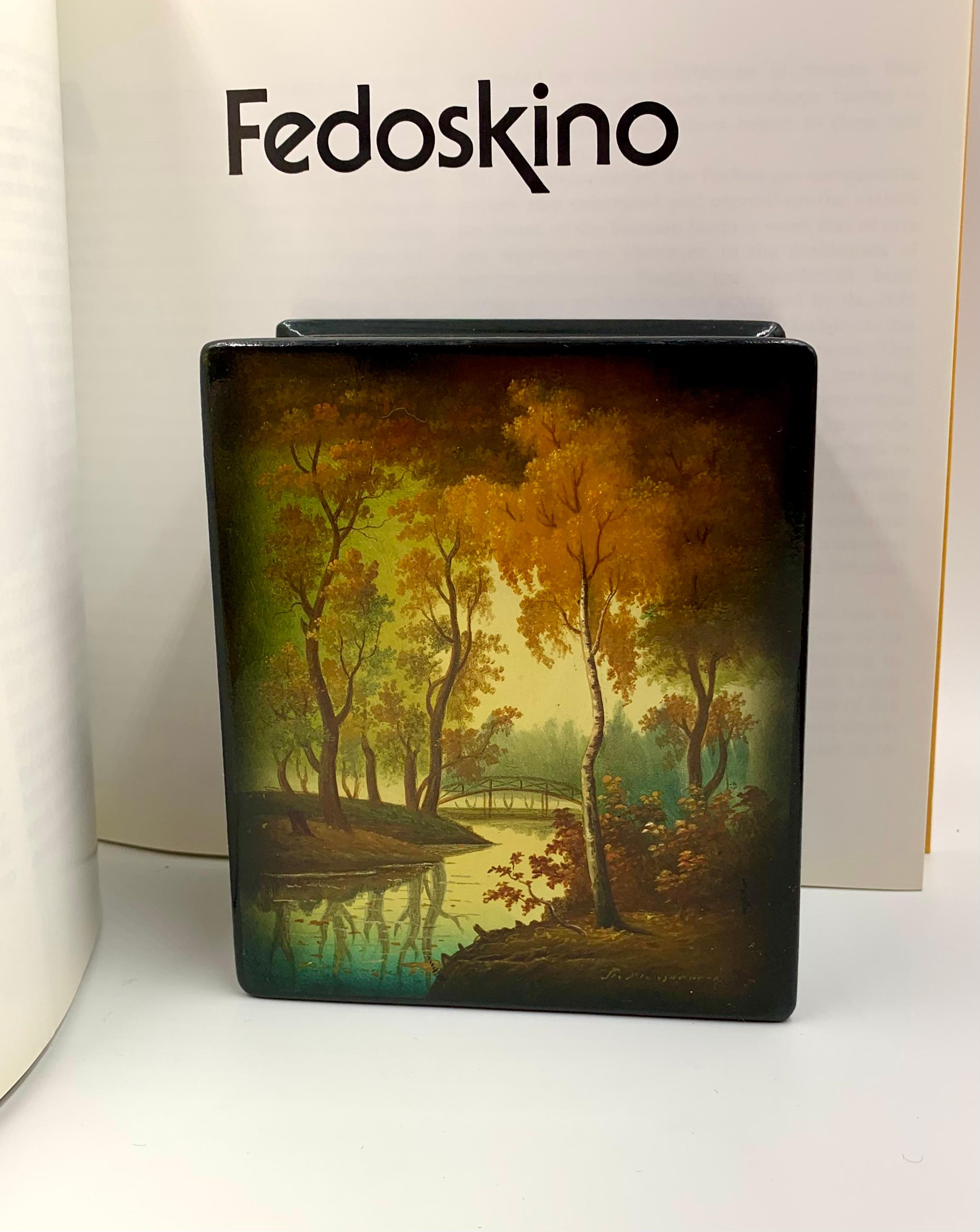 Scatola in lacca dipinta a mano di epoca sovietica Fedoskino di qualità museale, Autunno dorato, firmata dall'artista
20° secolo
Raffigura un idilliaco paesaggio autunnale con un romantico ponte su un ruscello fermo con i riflessi degli alberi