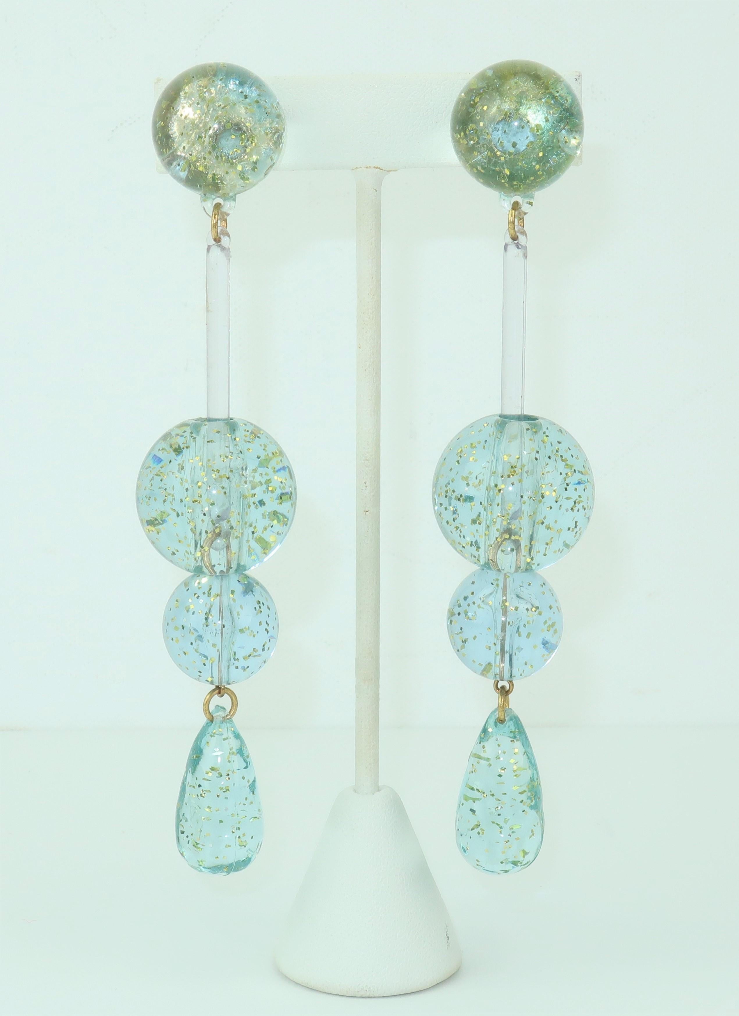 These 1960's acrylic drop earrings have a go-go girl look and a period perfect space age vibe.  Constructed with light ice blue orbs and teardrops highlighted with gold flecks and suspended from the clip on bases by clear rods and brass rings. 