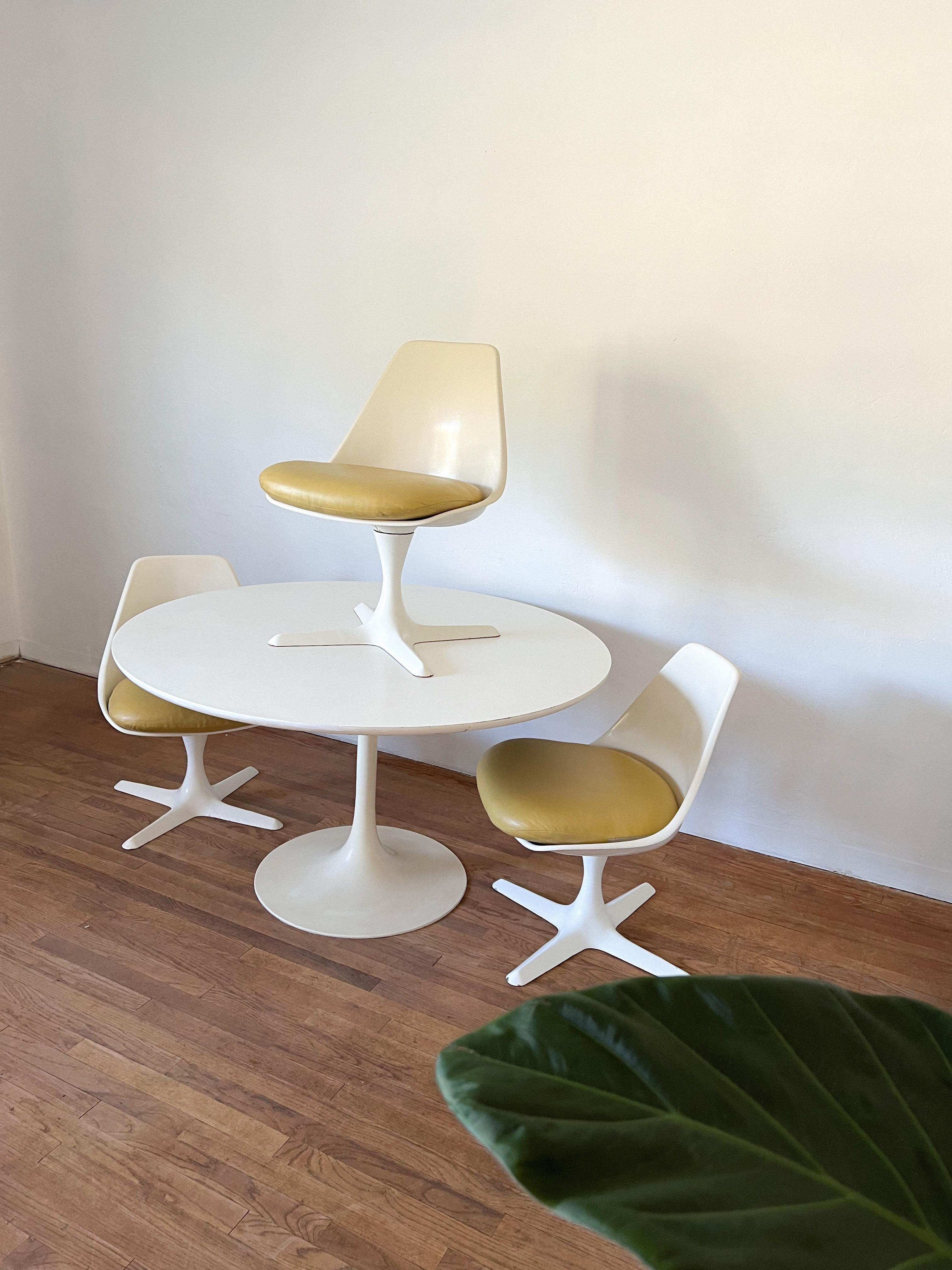 Space Age dining room by Maurice Burke for Arkana in Bath, England. It consists of a table with a tulip base and 3 matching chairs with propeller style base. This is an iconic design from the early 1960s. All four chairs rotate and return to the