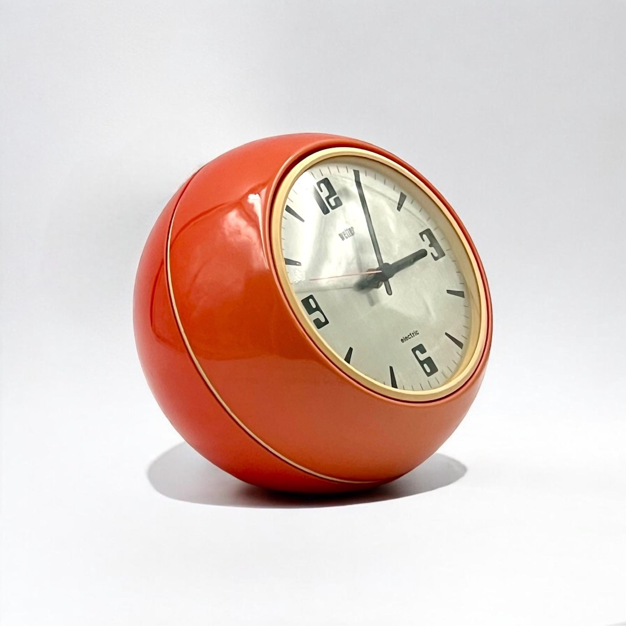 Enhance your space with the Space Age 70s clock by Wetter, a prime example of German industrial design from the Seventies. The orange plastic housing and clear dome cover reflect the bold yet functional aesthetic that defined this era.

At the core