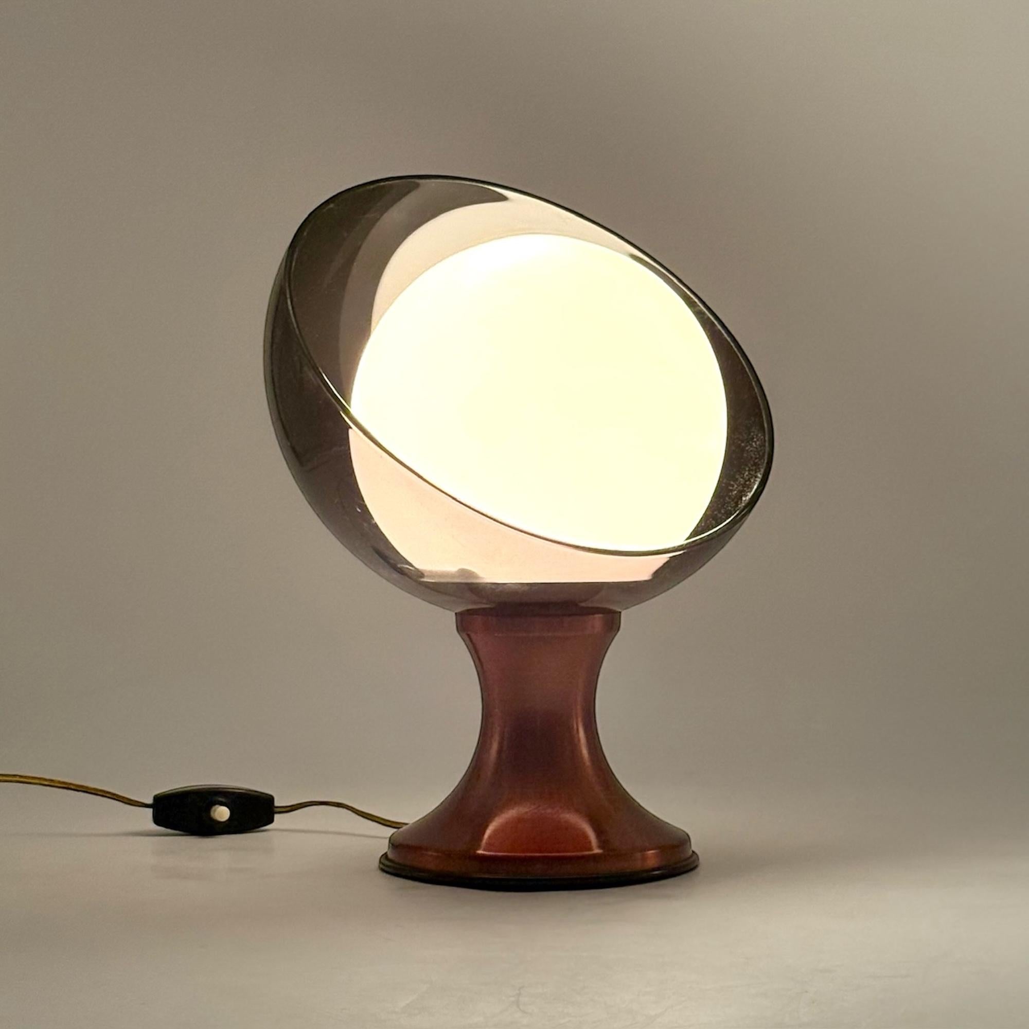 This Italian-made 1970s Space Age table lamp exemplifies the bold, futuristic design of the era. Its tulip-shaped bronze-effect metal base seamlessly complements the smoky grey lucite shade, while the white opaline glass diffuser ensures a soft,