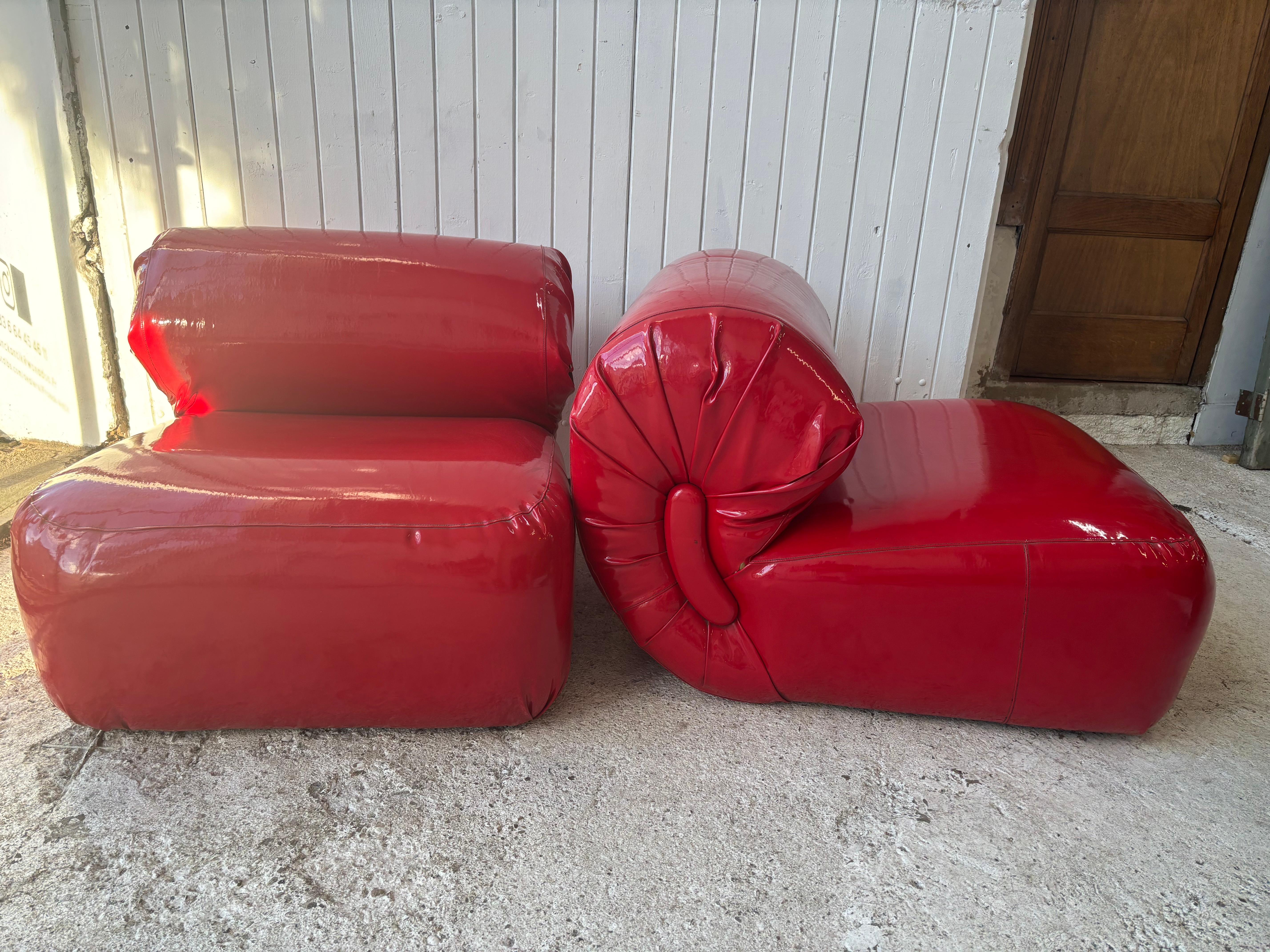 Wonderfull pair of red vinyl chairs with large Candy shaped folder 
We can imagine Brigitte Bardot like model 

These armchairs seem to be iconic pieces of 1970s design. Their appearance is reminiscent of the style of the famous designer Michel