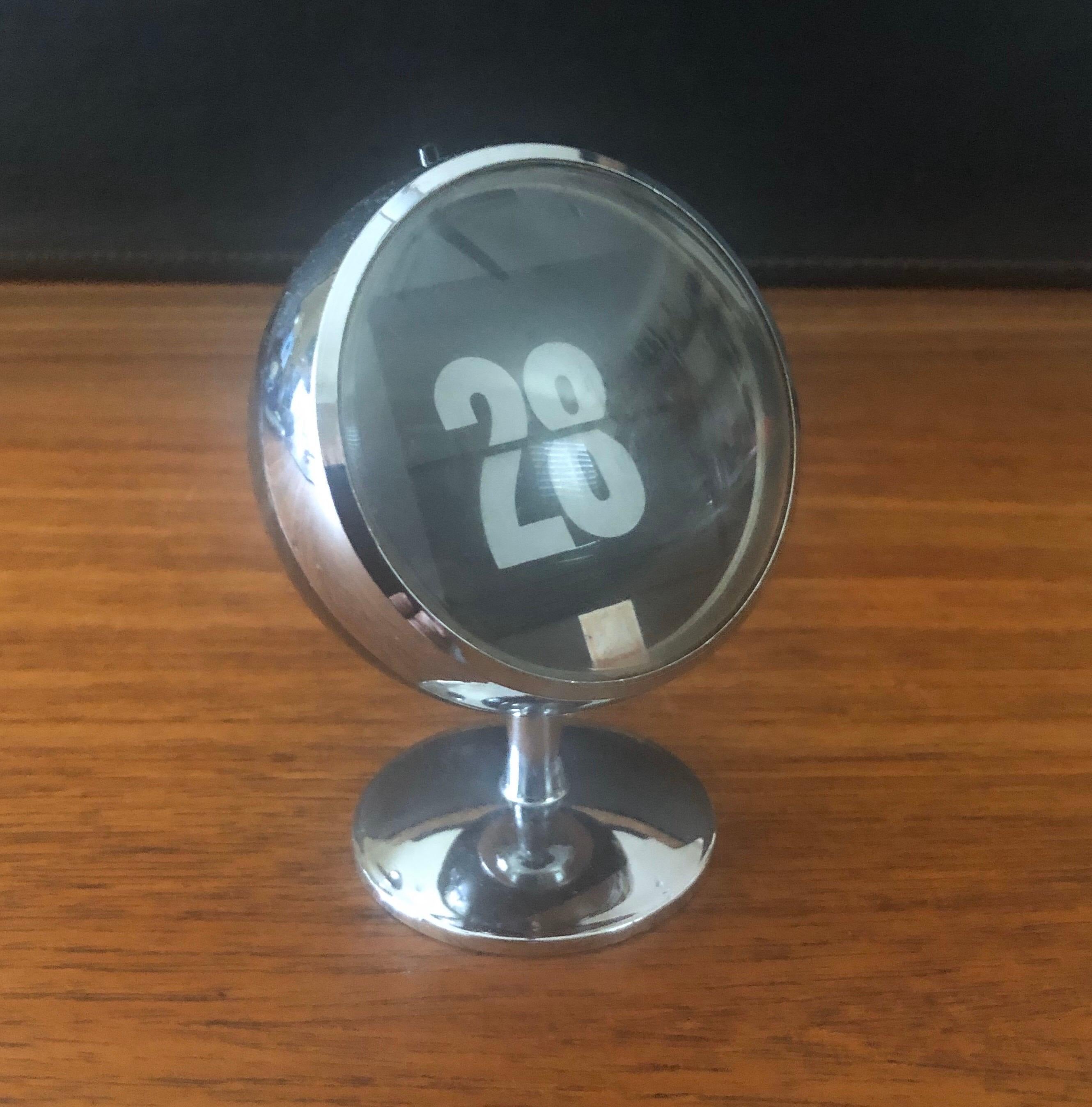 A very cool and hard to find Space Age atomic perpetual flip date calendar, circa 1970s. The piece has a button on top that when pushed flips the date number; goes from 1 to 31. Made of black, chrome and clear plastic.