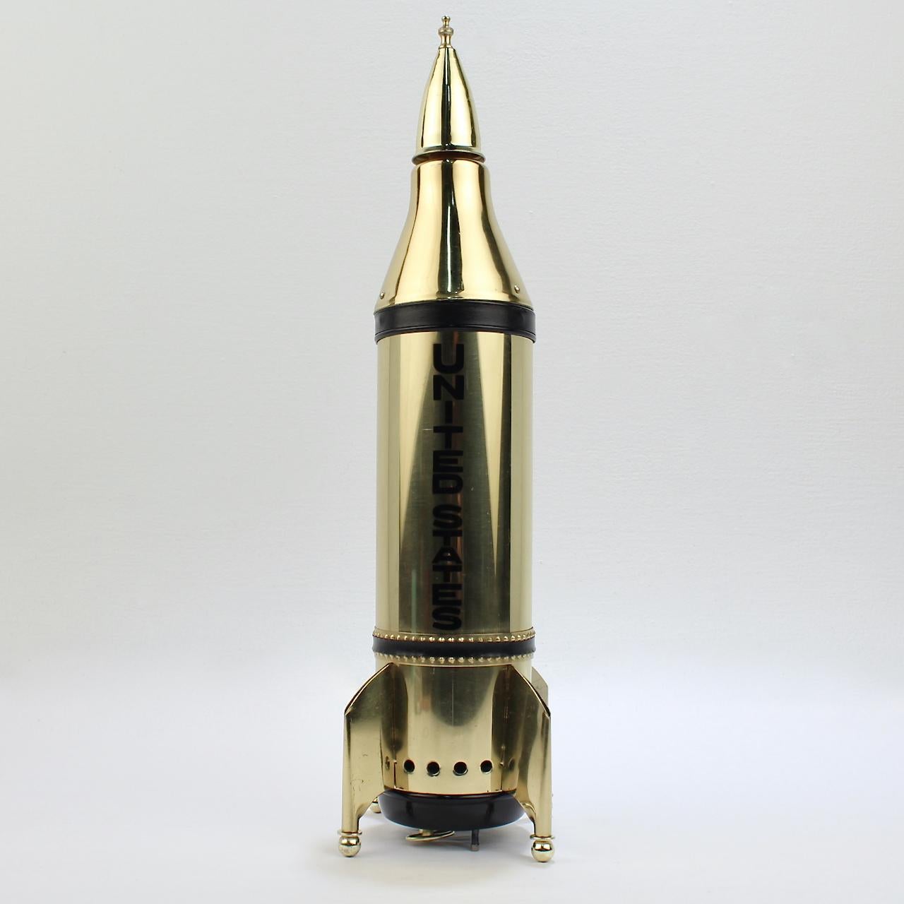 A rare, unused midcentury novelty decanter.

In the form of a rocket ship. 

And, of course, what rocket ship is complete without an integral wind up music box!

At its base is a key-wind music box that plays the tune - 'How Dry Am