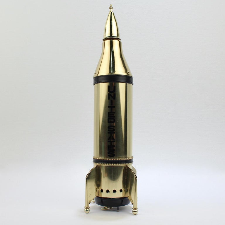 A rare, unused midcentury novelty decanter.

In the form of a rocket ship. 

And, of course, what rocket ship is complete without an integral wind up music box!

At its base is a key-wind music box that plays the tune - 'How Dry Am