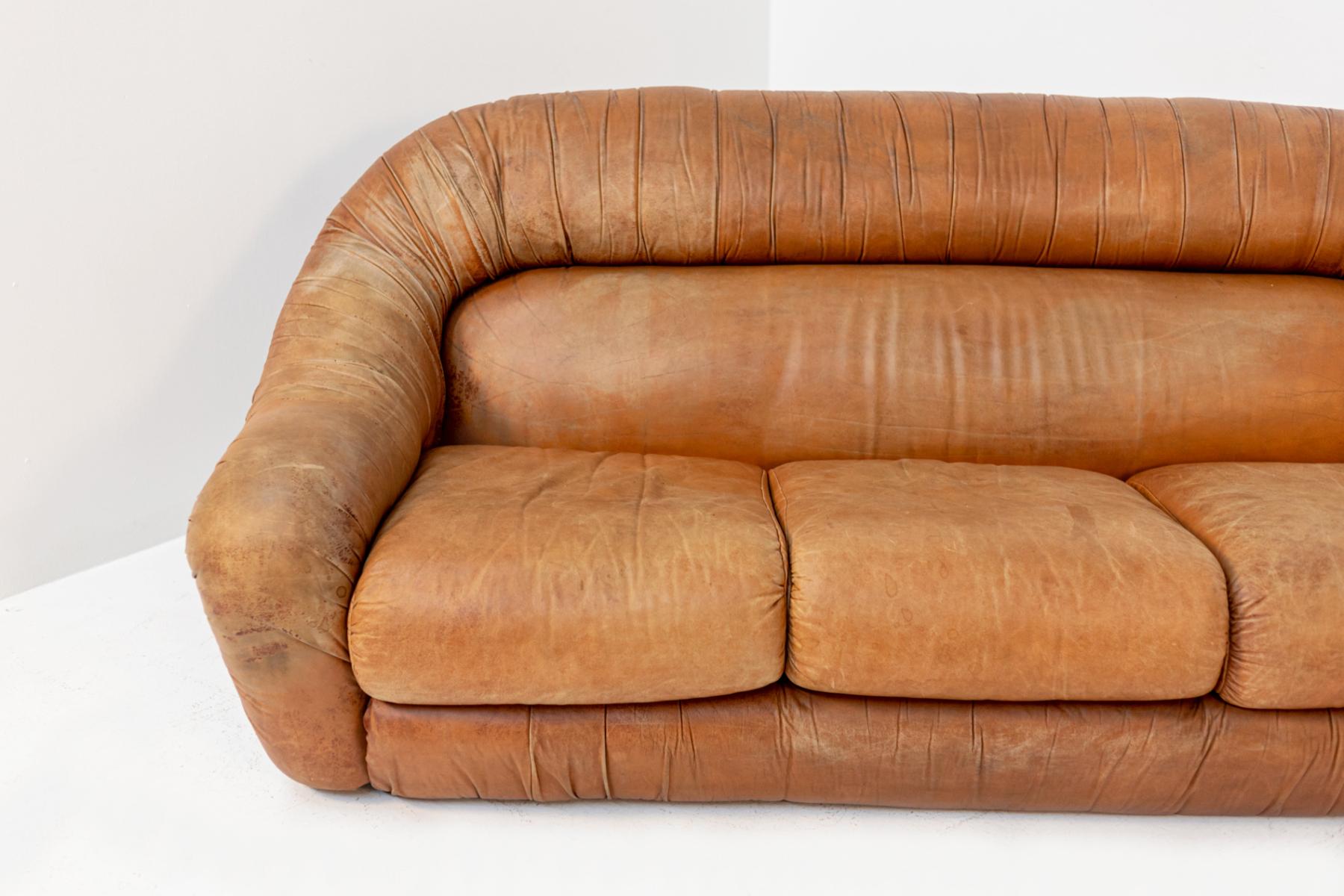 Gorgeous brown leather sofa in 1970s Space Age style.
The sofa has three seats and is fully upholstered in brown leather. It is very particular for its very round and soft shapes.
Each seat is composed of soft cushions, the side arms are one with