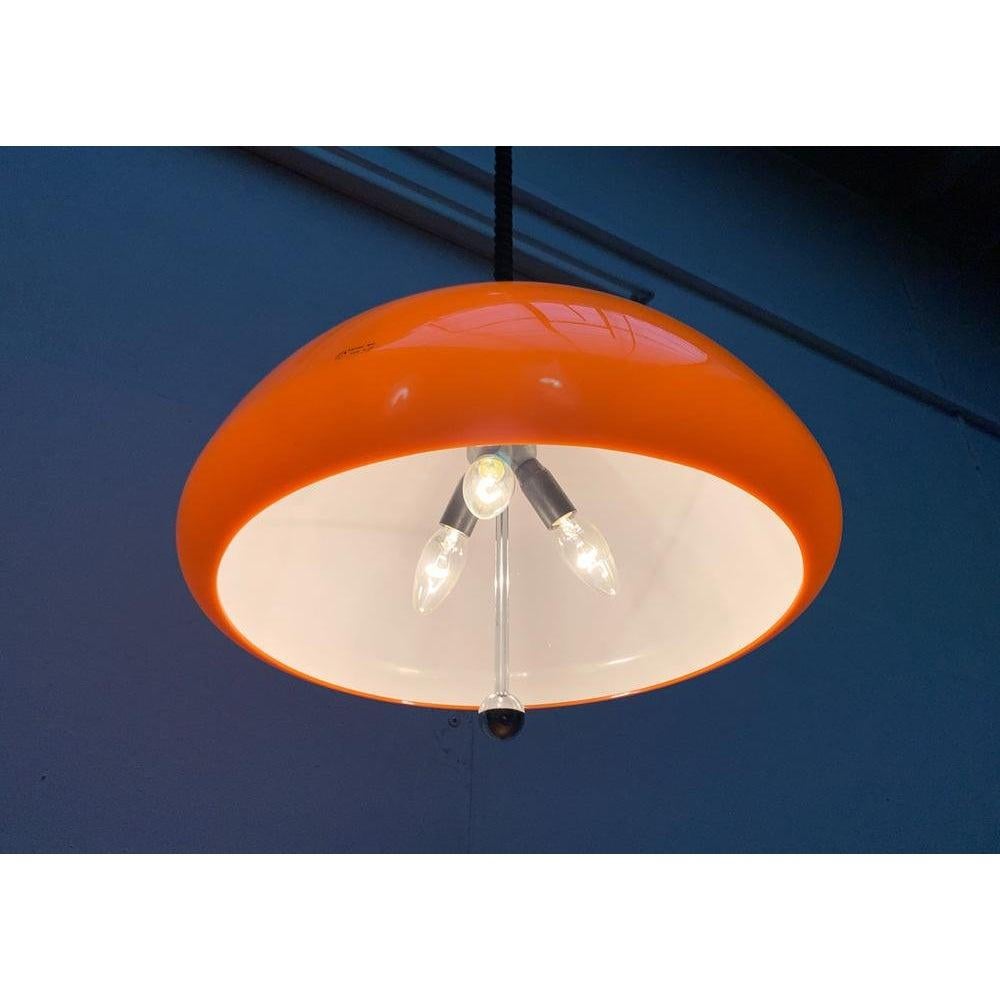 Rara lampada a sospensione a treno di Guzzini.

Il grande paralume in plastica è di colore arancione. Lo schermo è bianco all'interno. In questo modo, la lampada emette una luce bianca molto funzionale. Esternamente, il paralume si presenta come un