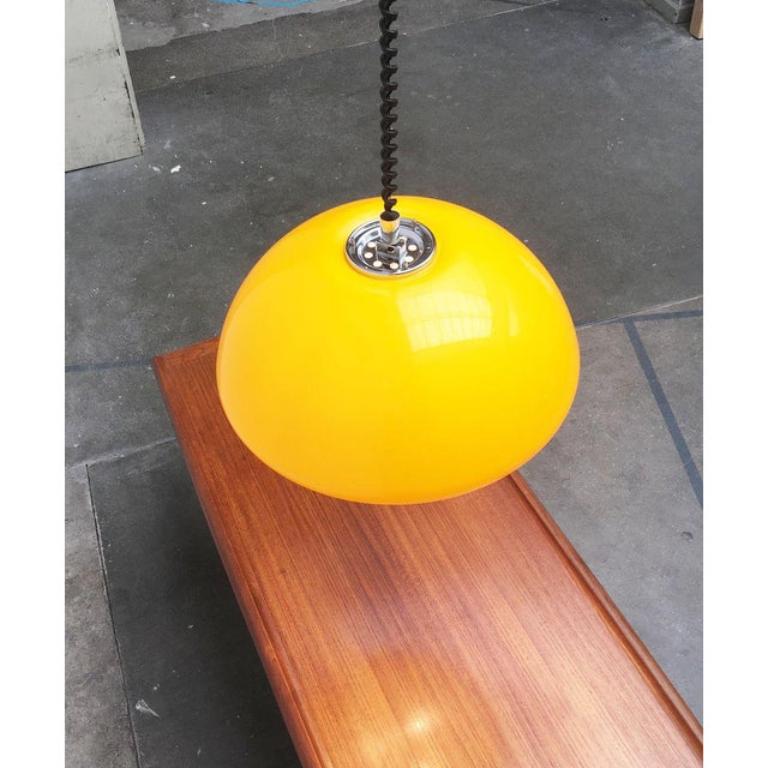 Rara lampada a sospensione a treno di Harvey Guzzini.

Il grande schermo in plastica è di colore giallo. L'interno dello schermo è bianco. In questo modo, la luce completamente funzionale proietta la luce bianca verso il basso. Esternamente lo