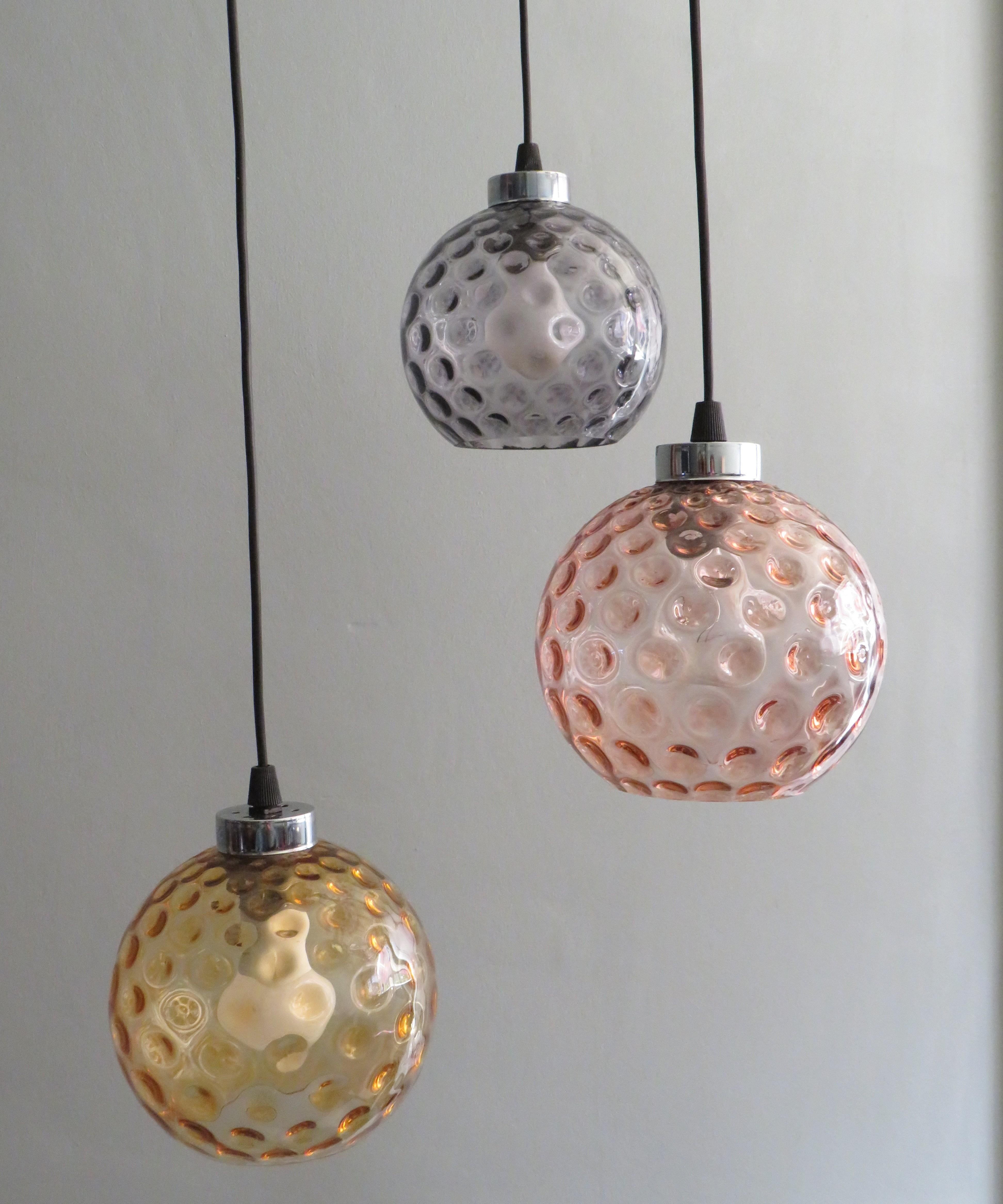Cascade chandelier, Peill and Putzler, Germany 1960-1970.
Hanging lamp with 3 bubble glass spheres, pink, amber and mauve colored.
Each sphere can be easily adjusted to the desired height. 
The ceiling plate is made of black lacquered metal and