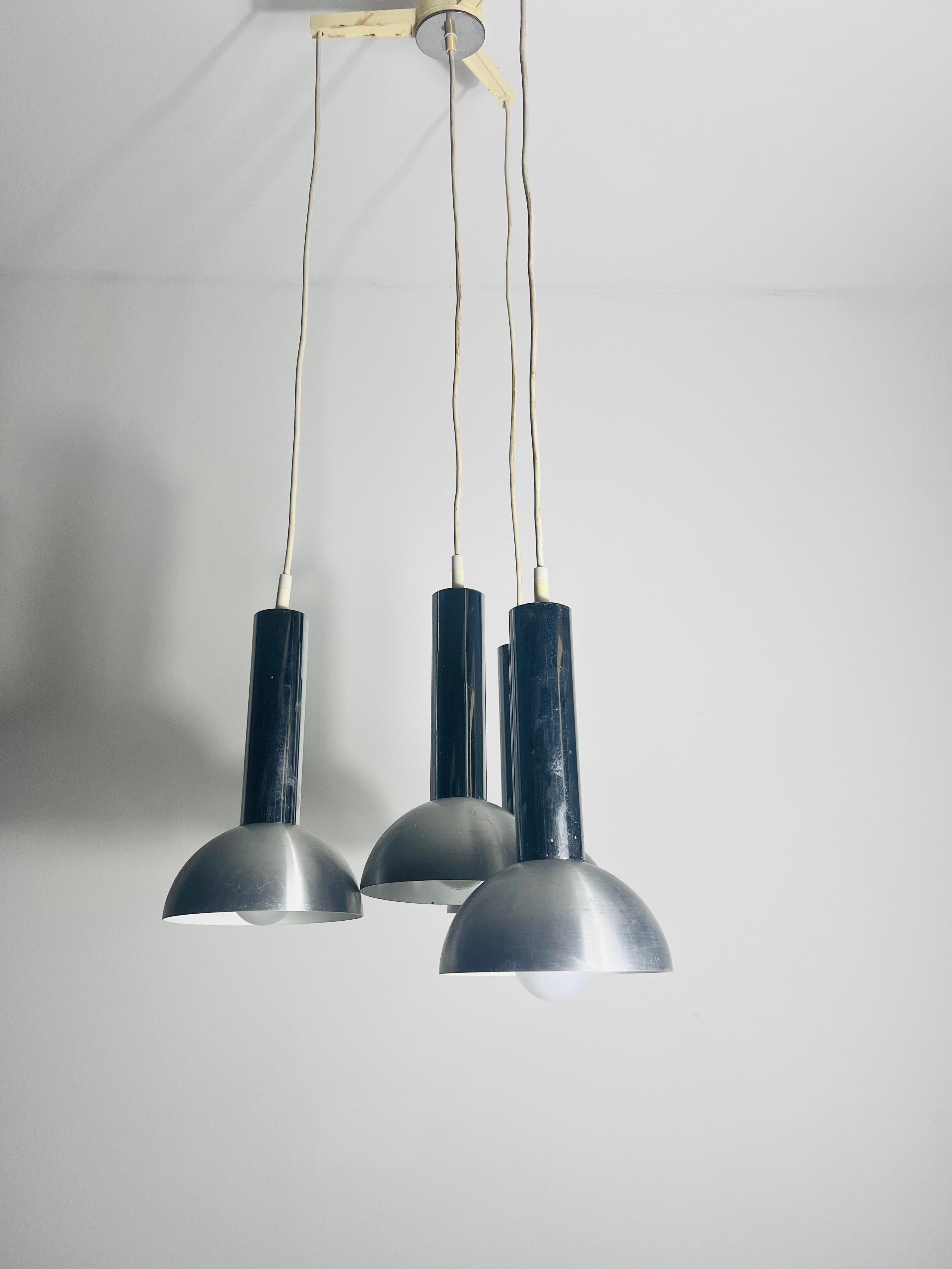 Stupenda lampada da soffitto a cascata dell'era spaziale degli anni '70, con quattro paralumi in metallo dal design elegante e futuristico. Questo pezzo iconico cattura l'essenza dell'era dell'A Space, con le sue forme geometriche pulite e la