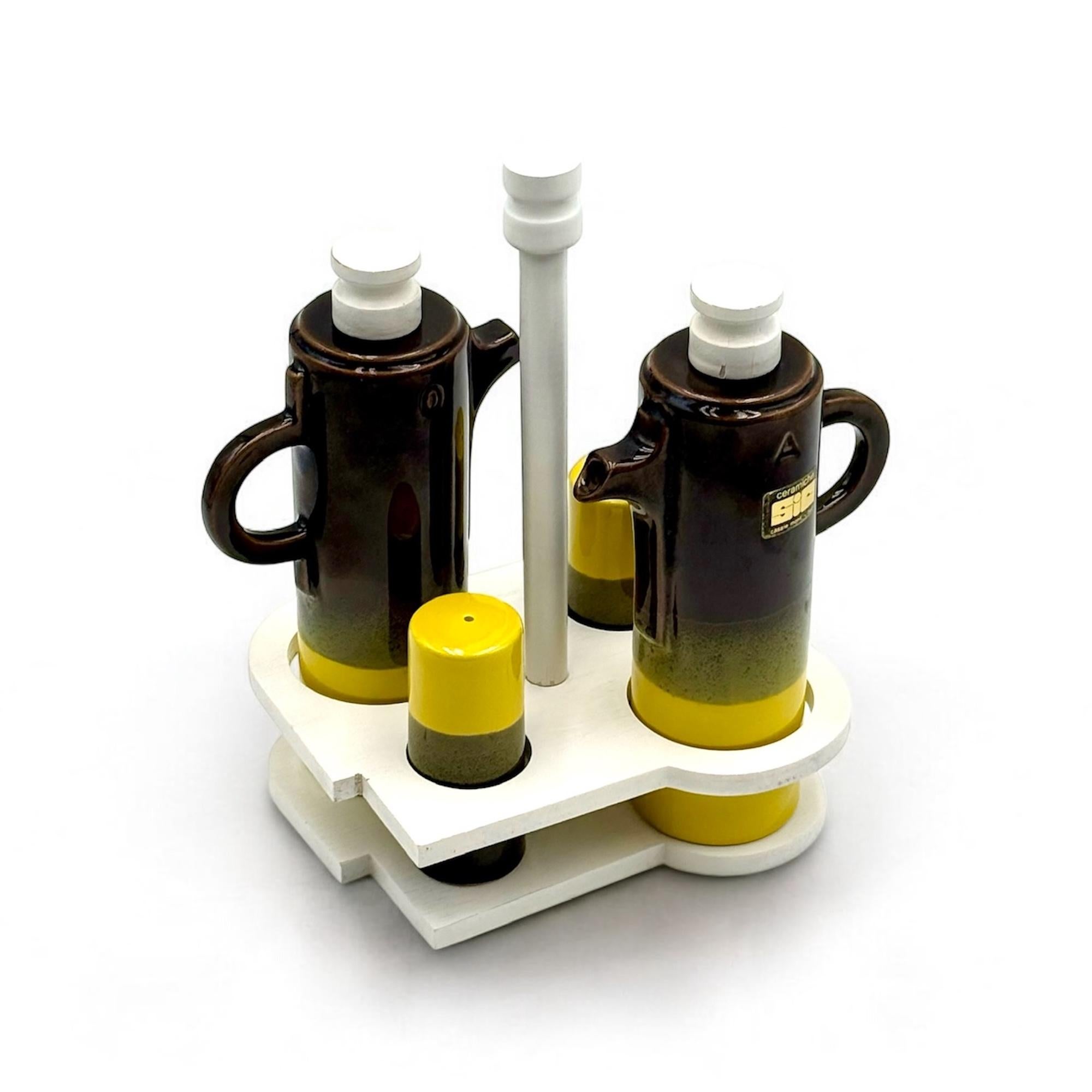 Set de condiments des années 70 de SIC, fabriqué en Italie. Cet ensemble complet de menage comprend quatre récipients en céramique - sel, poivre, huile et vinaigre - logés dans un support sculptural en bois blanc.

Chaque pièce présente une glaçure
