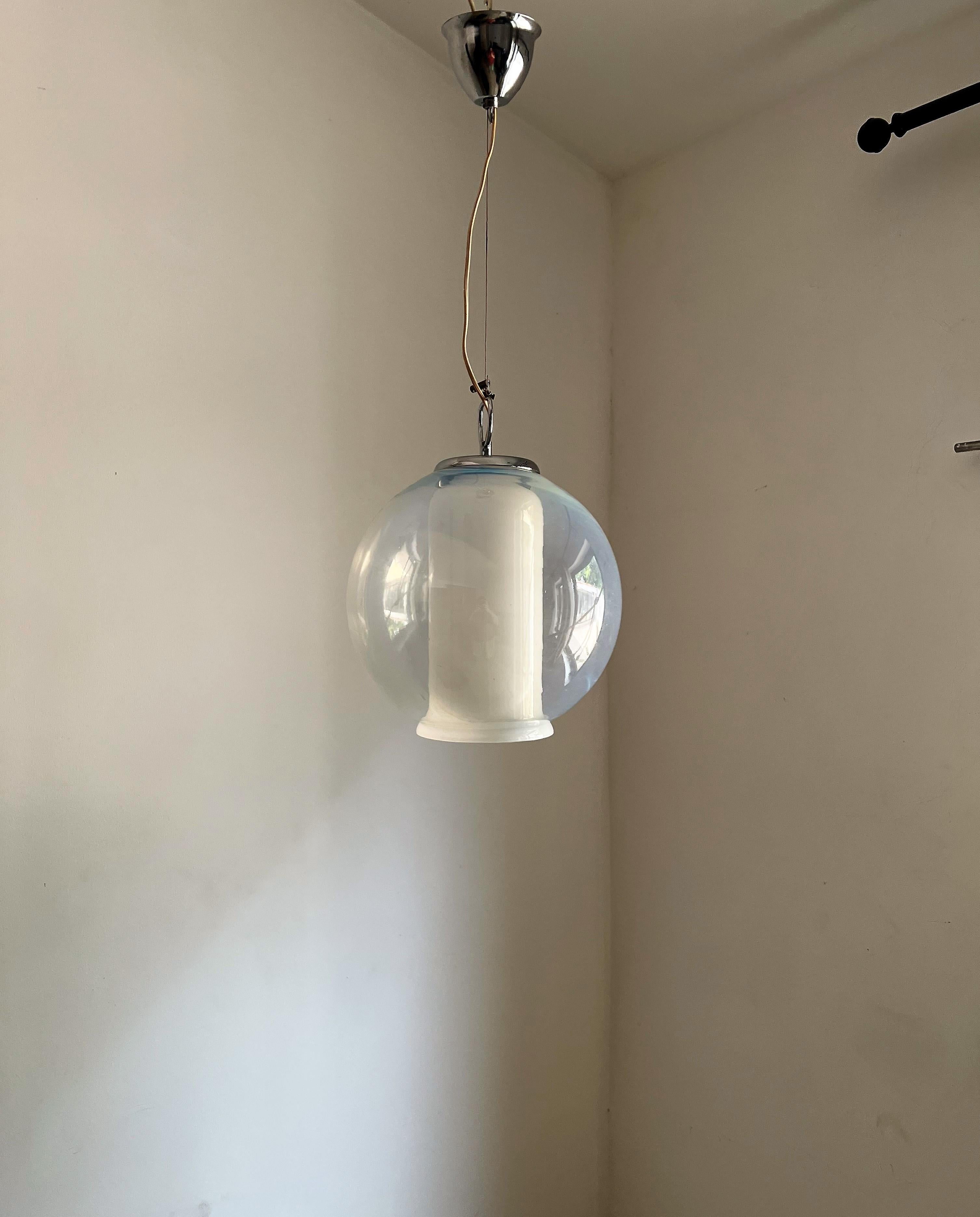 Space age pendant light by Carlo Nason for Mazzega, circa 1970.
This lamp consists of 2 separate pieces a core piece in white and the sorrounding sphere in opalescent blue Murano glass.
The lamp holds one e 27 bulb and has been recently rewired