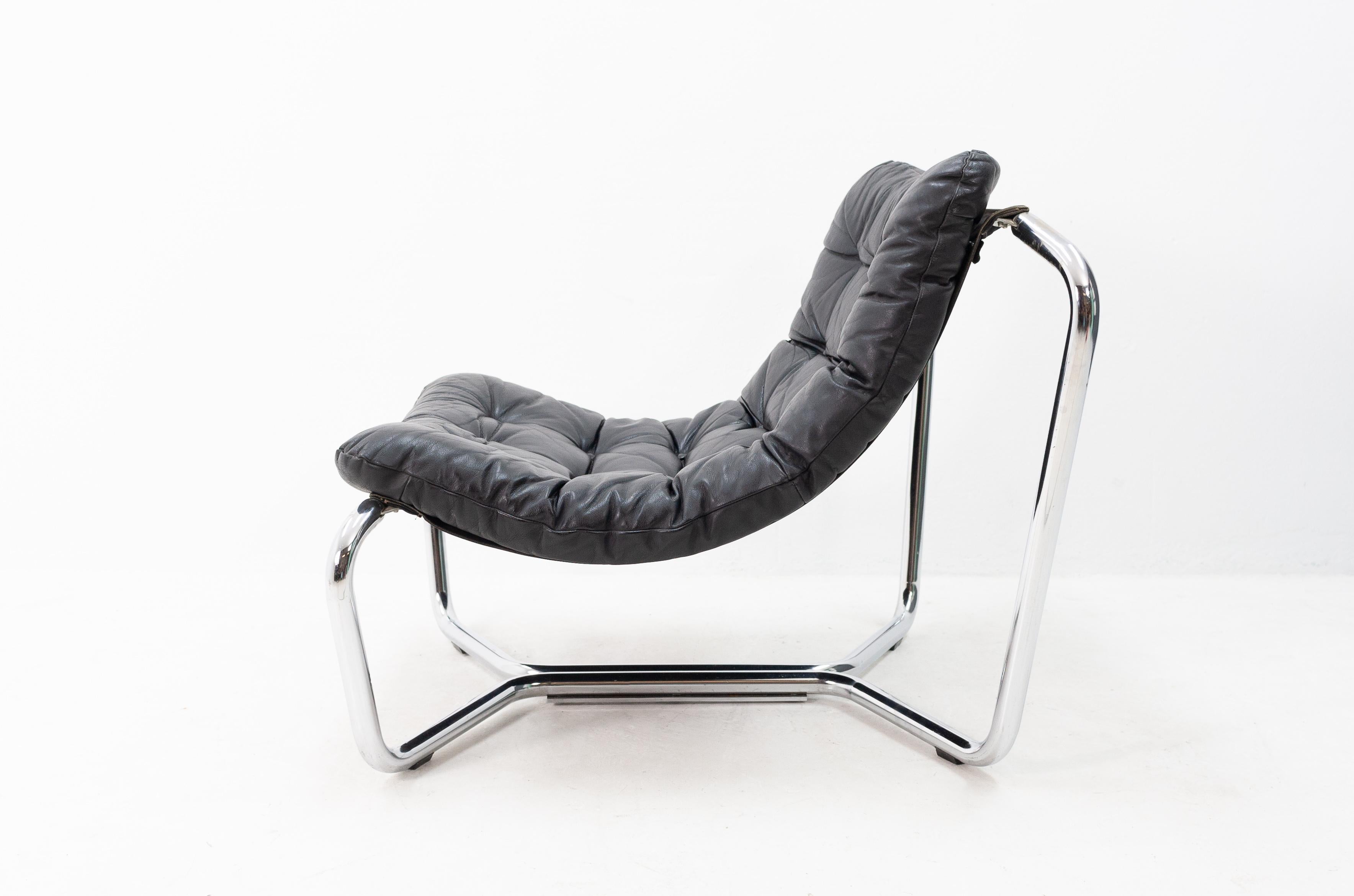 Very nice looking lounge chair. Chrome tube frame with a canvas sling and a tufted black leather seat cushion. Looks very much like an Ingmar Relling chair. There's some chrome wear/discoloration on the top right corner of the frame.