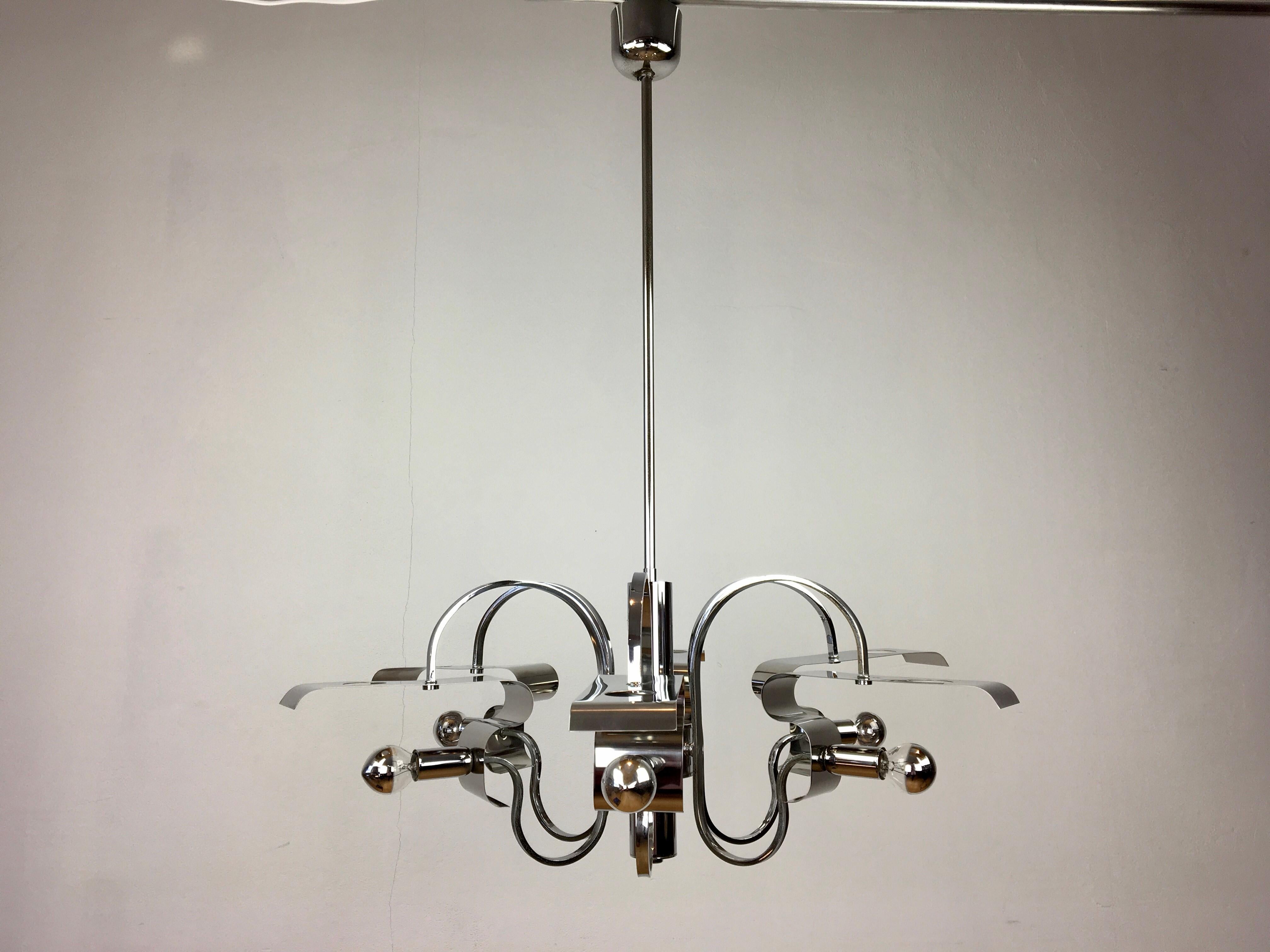 Space age chrome chandelier. 
A chromed metal chandelier with beautiful shapes / design. 
Curlings, rectangular, holes to leave the light through.
A 6 - armed chandelier with 6 light points with E14 fittings.
With this type of lamp it's