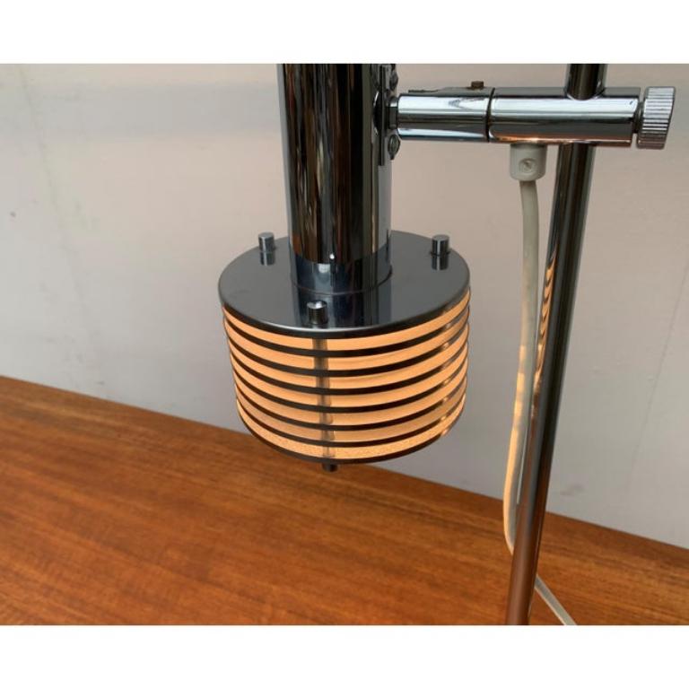 Rare space age table lamp.

A distinctive detail of this lamp is the reflector shade, which is dissolved in slats. These give a clear view of the illuminant and and seal it off at the same time. The lamp head can be adjusted in height on the shaft