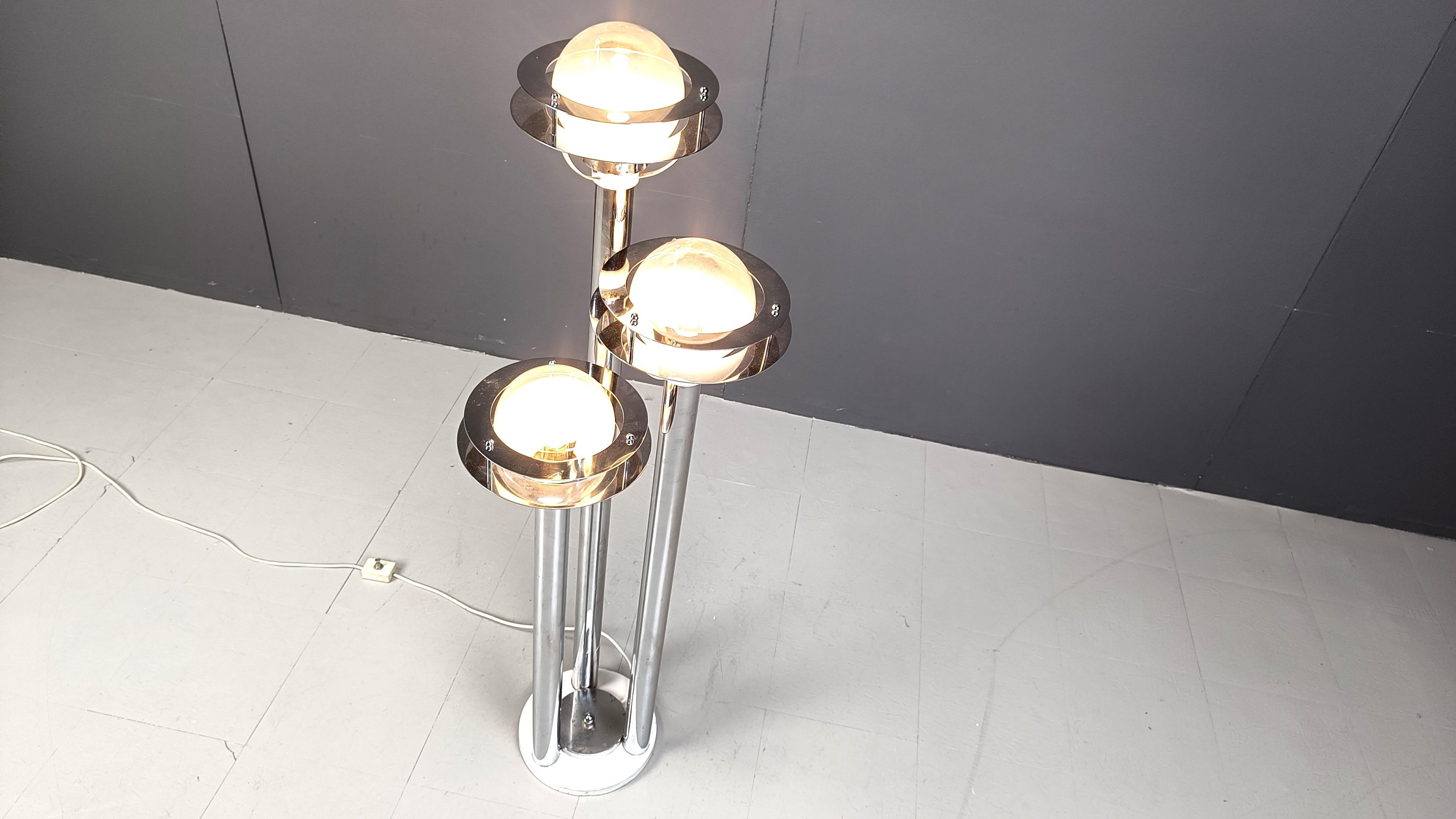 Lampada da terra dal sorprendente design vintage dell'era spaziale con tre paralumi simili a quelli di Saturno.

I paralumi sono composti da anelli cromati e sfere di vetro parzialmente smerigliato.

La lampada da terra emette una bellissima