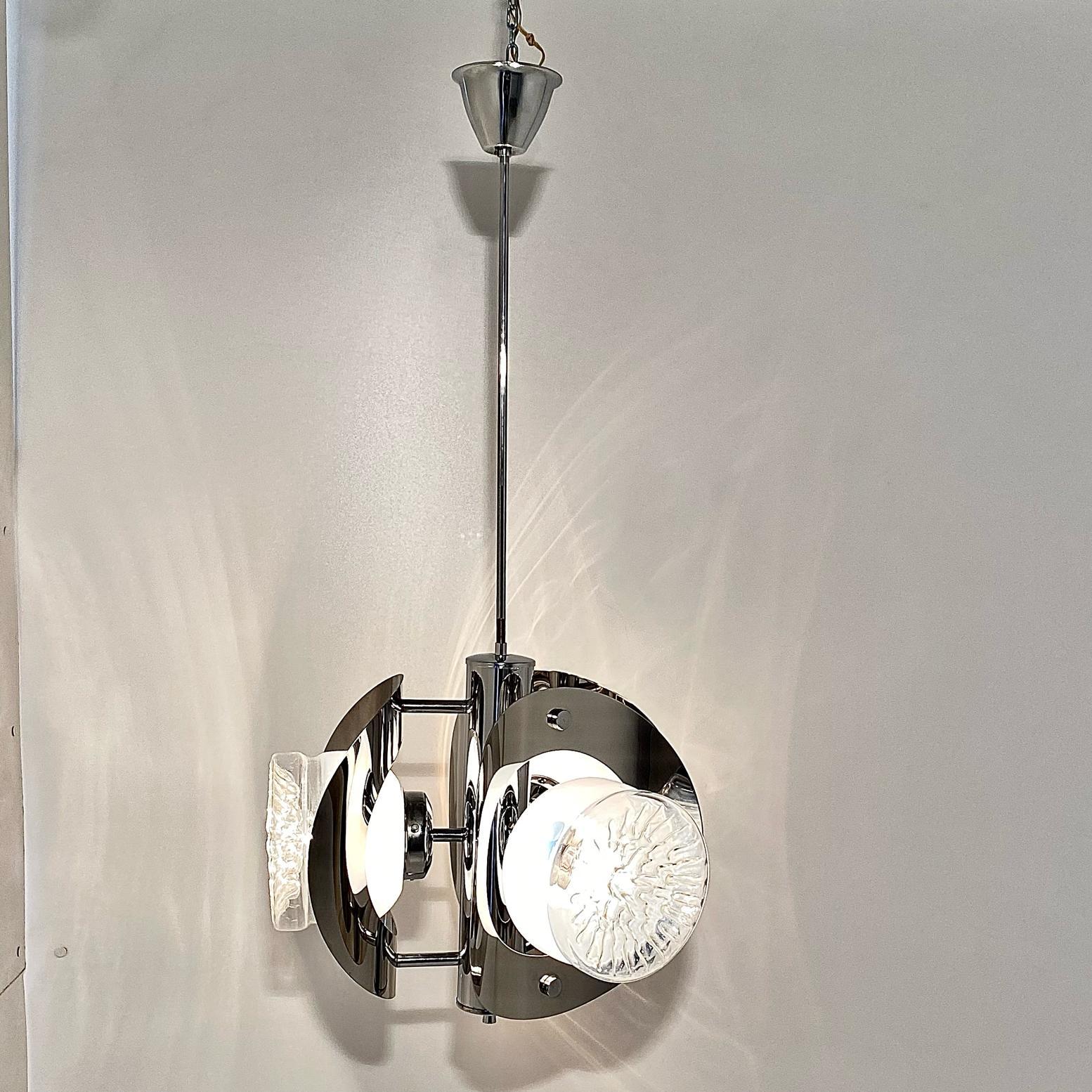 Un chadelier chromé de l'ère spatiale des années 1970, Carlo Nason pour Mazzega. Fabriqué en Italie par Mazzega ltd et conçu par Carlo Nason. Structure en acier chromé avec trois spots lumineux en verre de Murano. L'objet a été restauré comme suit