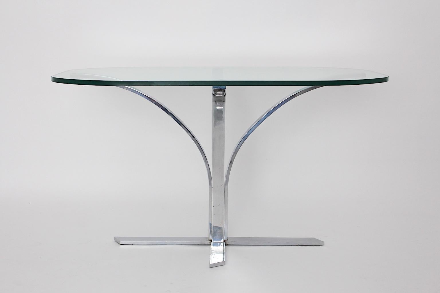 A space age chromed metal vintage dining table or writing table, which was designed and manufactured, 1960s, Germany.
The base is a chromed metal construction, which holds a clear glass top with a thickness of 0.80 cm.
The design radiates the