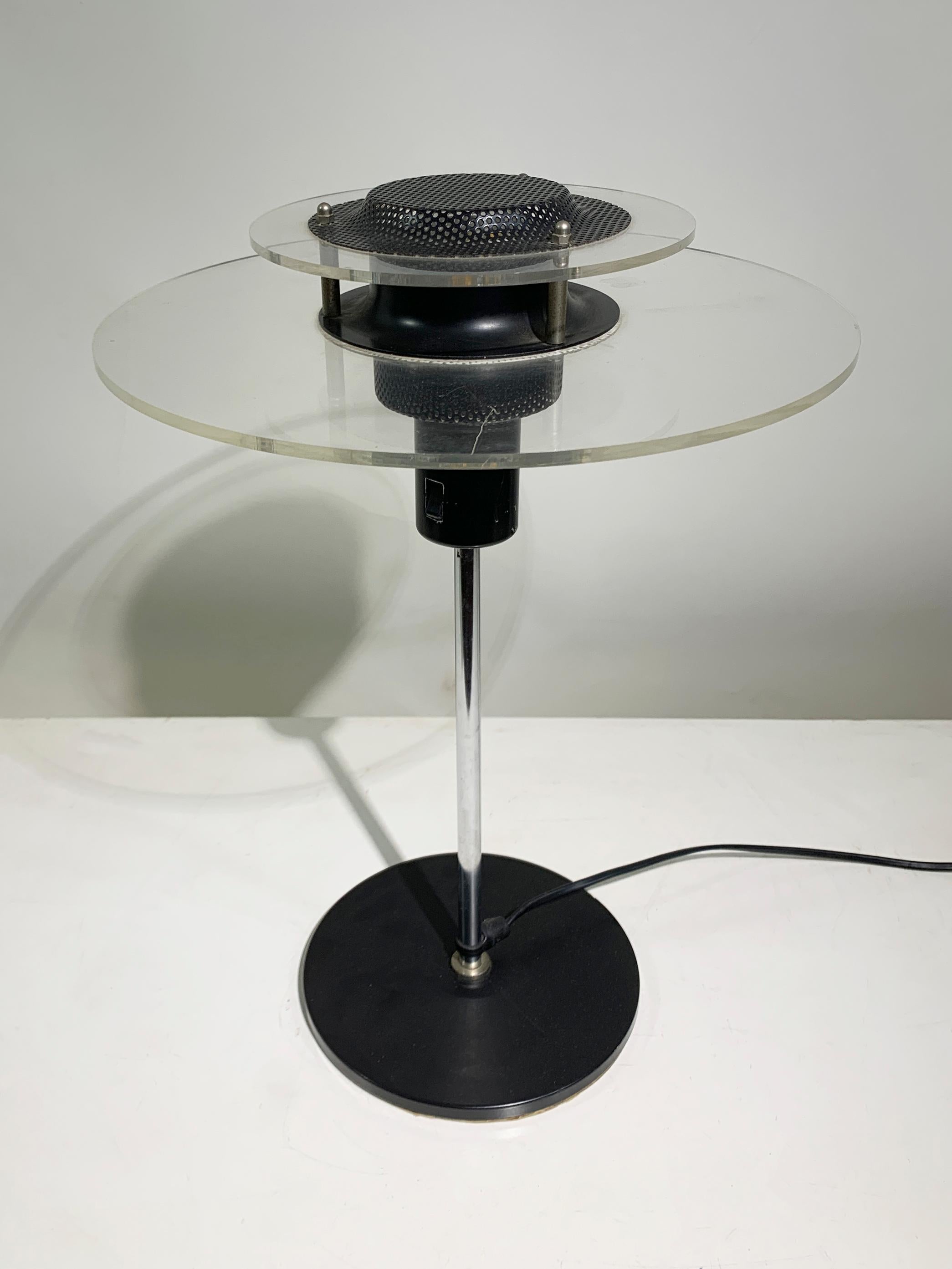A striking example of 1970s modernist design, this sculptural table lamp features a distinctive architectural silhouette, blending industrial and space-age aesthetics. The lamp comprises a black metal central body with perforated detailing, accented