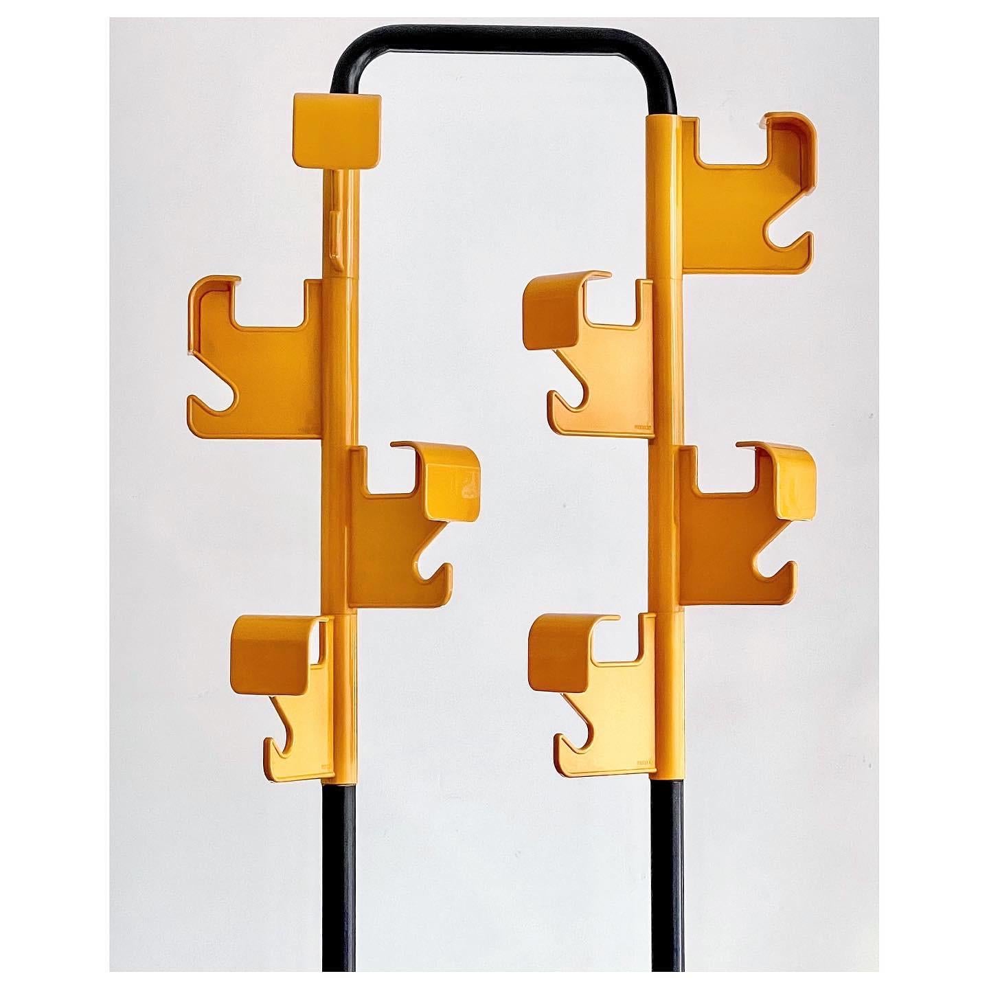 Colourful bright yellow coat rack by the French designer Jean-Pierre Vitrac for Manade, 1970s. 
The coat rack has a tubular structure of black painted metal, attached to a heavy square base, to catch any water from your umbrella. Two sets of 4