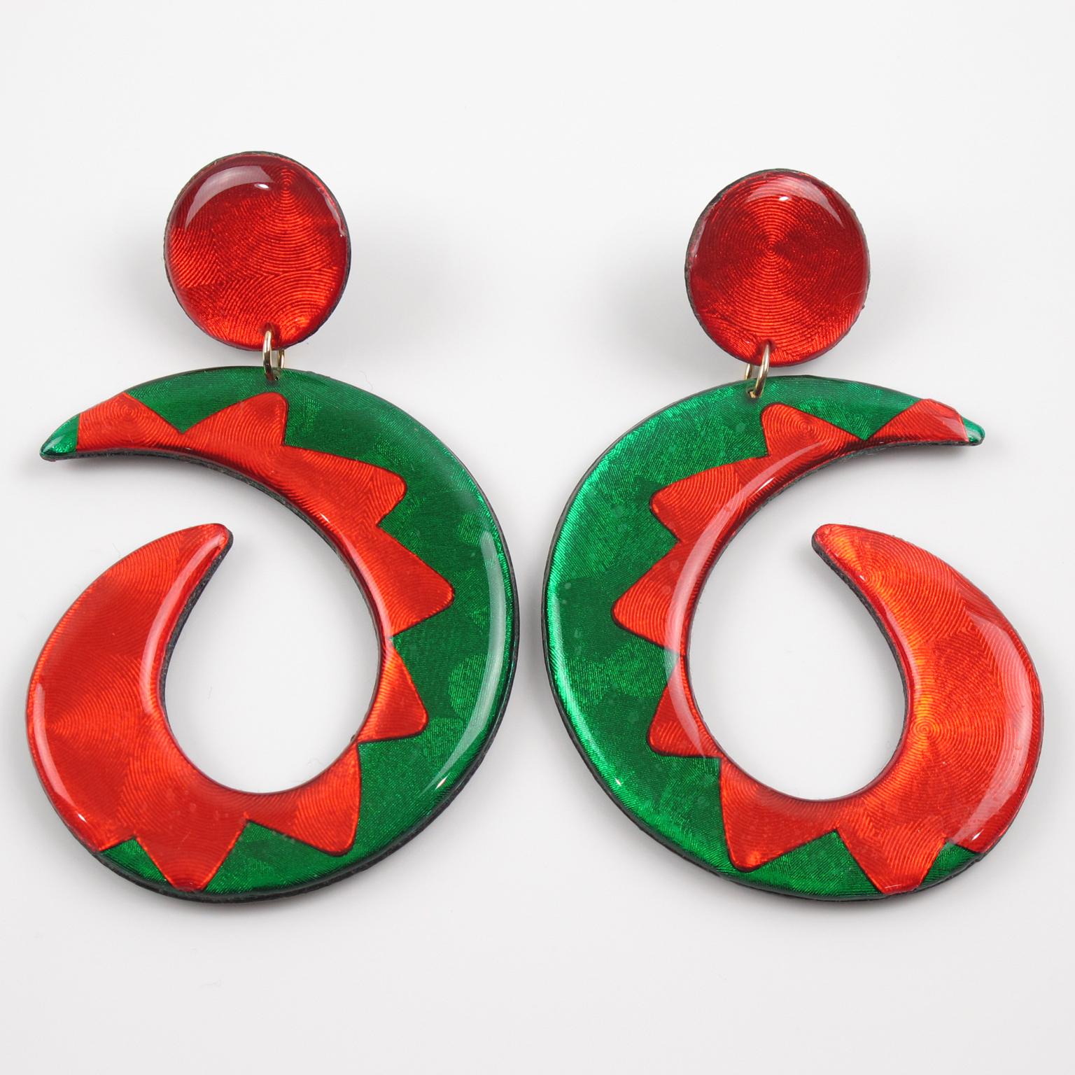 Questi impressionanti orecchini pendenti in lucite sono caratterizzati da una forma a lampadario oversize con un design a cerchio aperto di colore verde brillante e rosso neon, accentuato da una trama scintillante su sfondo nero. Questi pezzi sono