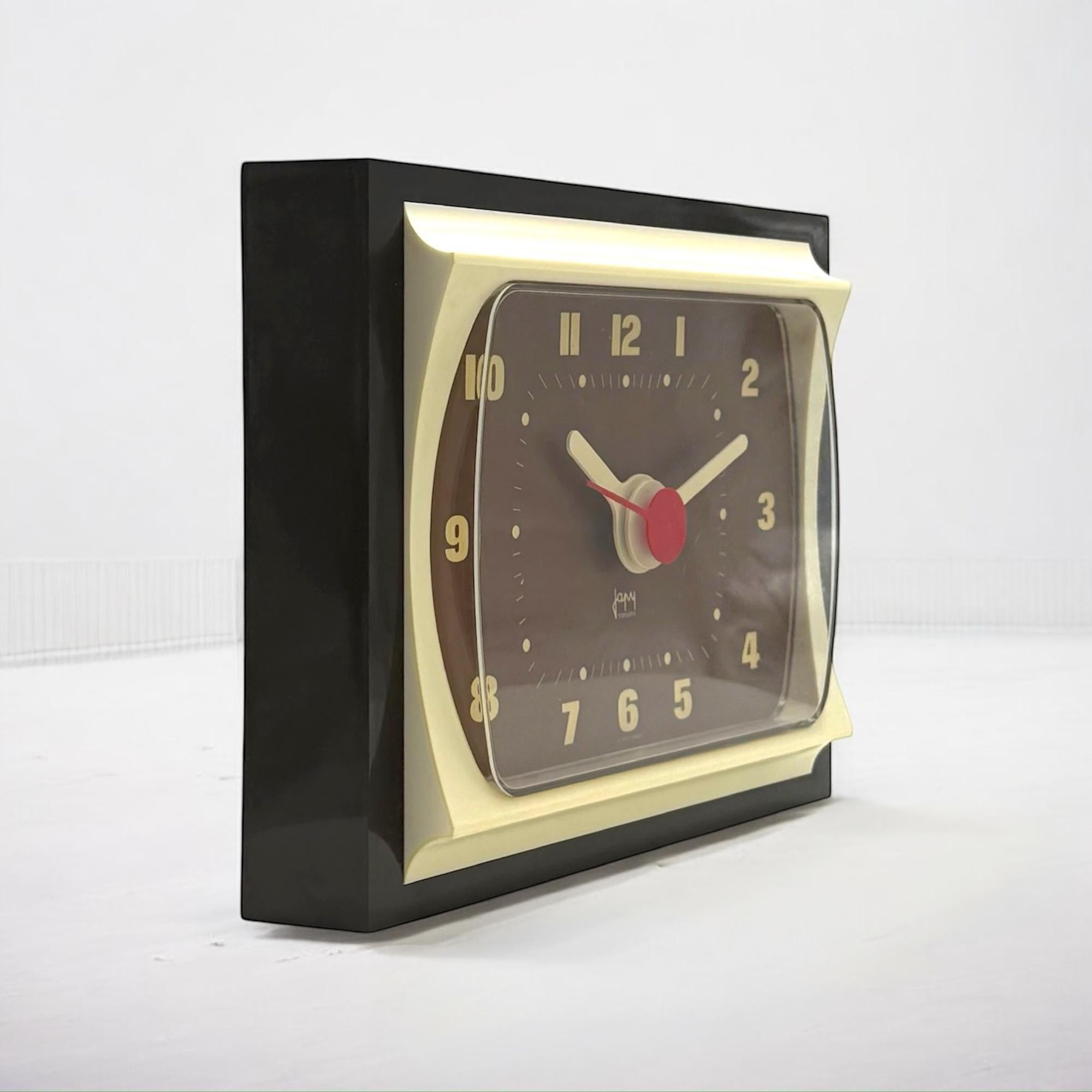 Cette horloge vintage des années 70 de Japy France dégage un charme rétro avec ses couleurs noir, marron et crème. Doté d'un cadre rectangulaire avec des détails incurvés, il capture l'essence du design moderne et vintage.

Ses grandes dimensions