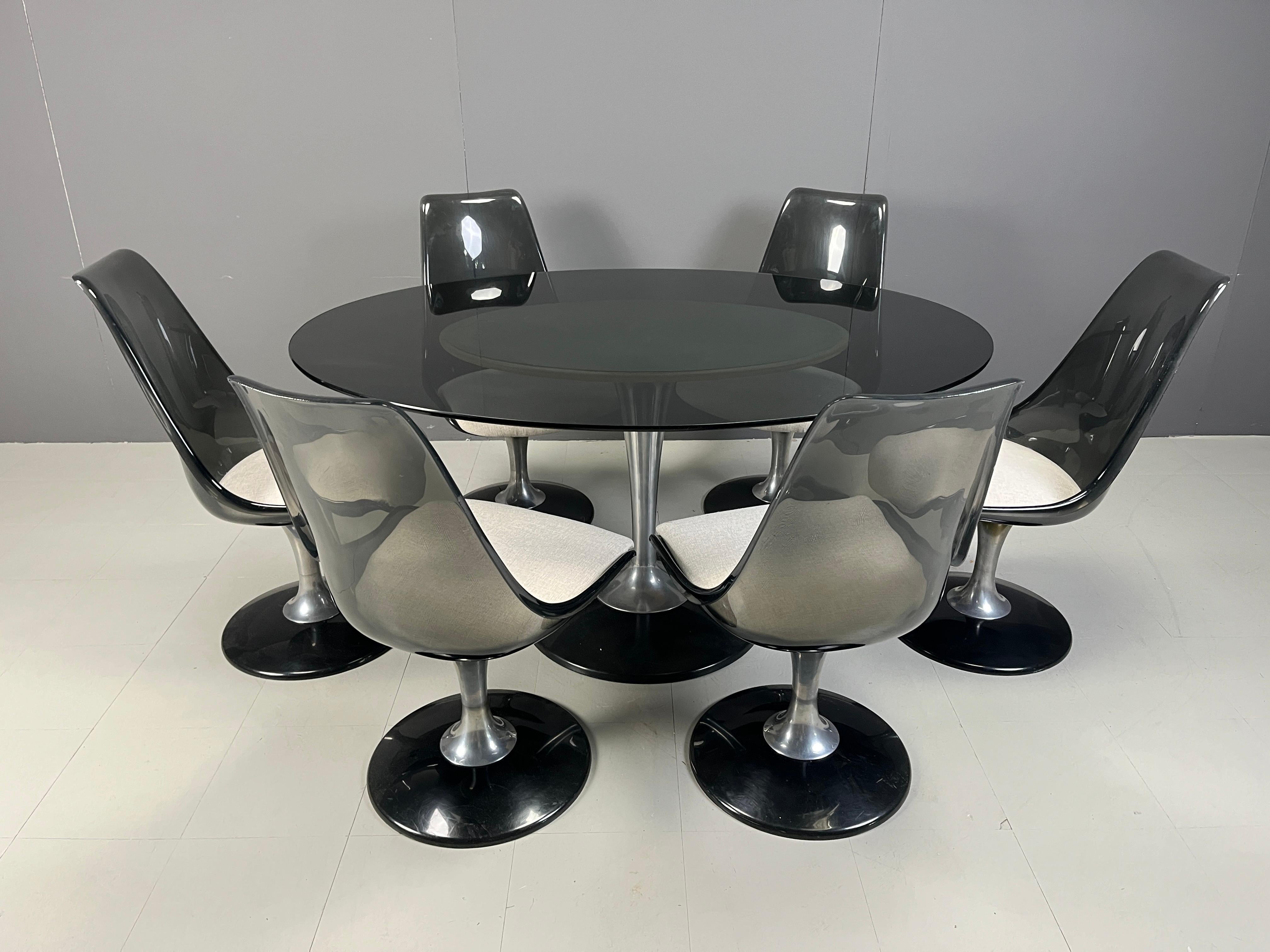 Space age tulip design dining set by Chromcraft manufactured in the USA.

The set consists of 6 dining chairs with black metal and aluminum bases and acrylic and fabric seats. The chairs can also swivel.

The table is made from a black metal tulip
