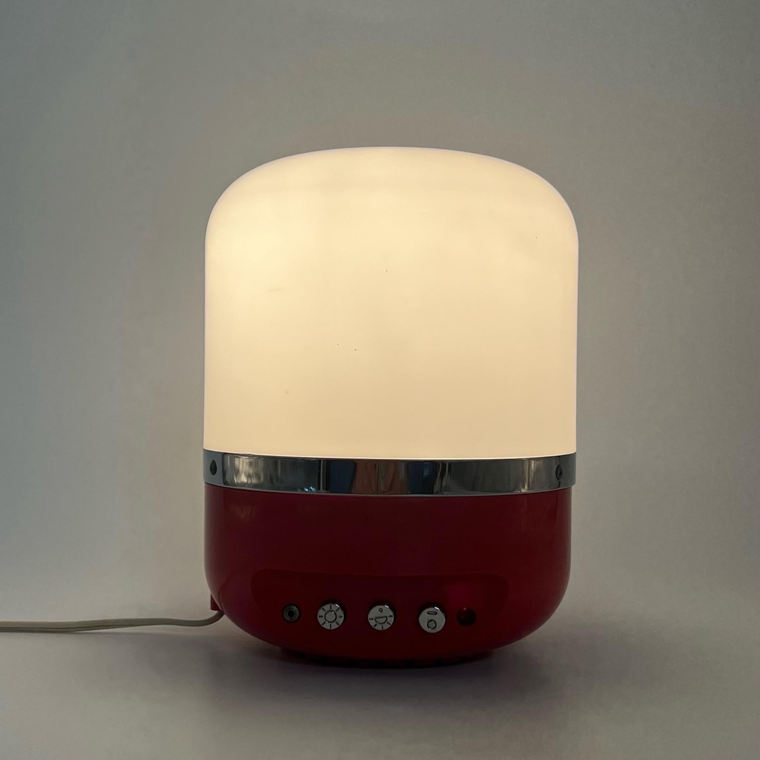 Iconic table / desk lamp Europhon designed by Adriano Rampoldi. This piece comes with the iconic flame red color perfectly matching the beige lampshade. The color combination and the rounded shape evoke the 70s atmospheres for a perfect vintage