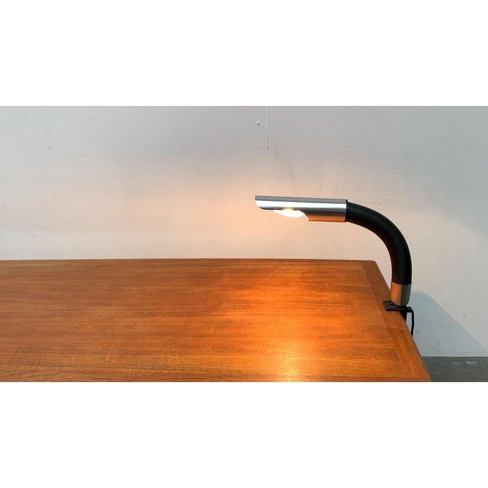 Space age table lamp with table clamp.

The head of the lamp is flexible via a swan neck. The contrast between the black tube element with the rib structure and the smooth surface of the aluminum is particularly important. This piece has an