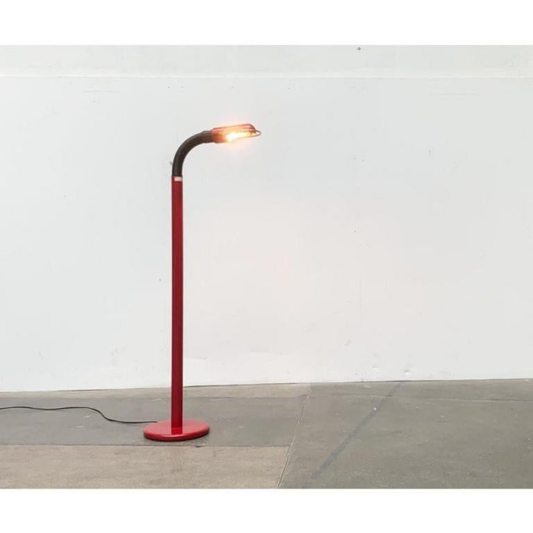 Lampadaire de la NO AGE avec un abat-jour rouge foncé.

La tête du Luminaire est conçue pour être mobile grâce à un col de cygne. Le contraste entre le tube noir à la structure nervurée et la surface lisse du corps de lampe laqué en couleur est