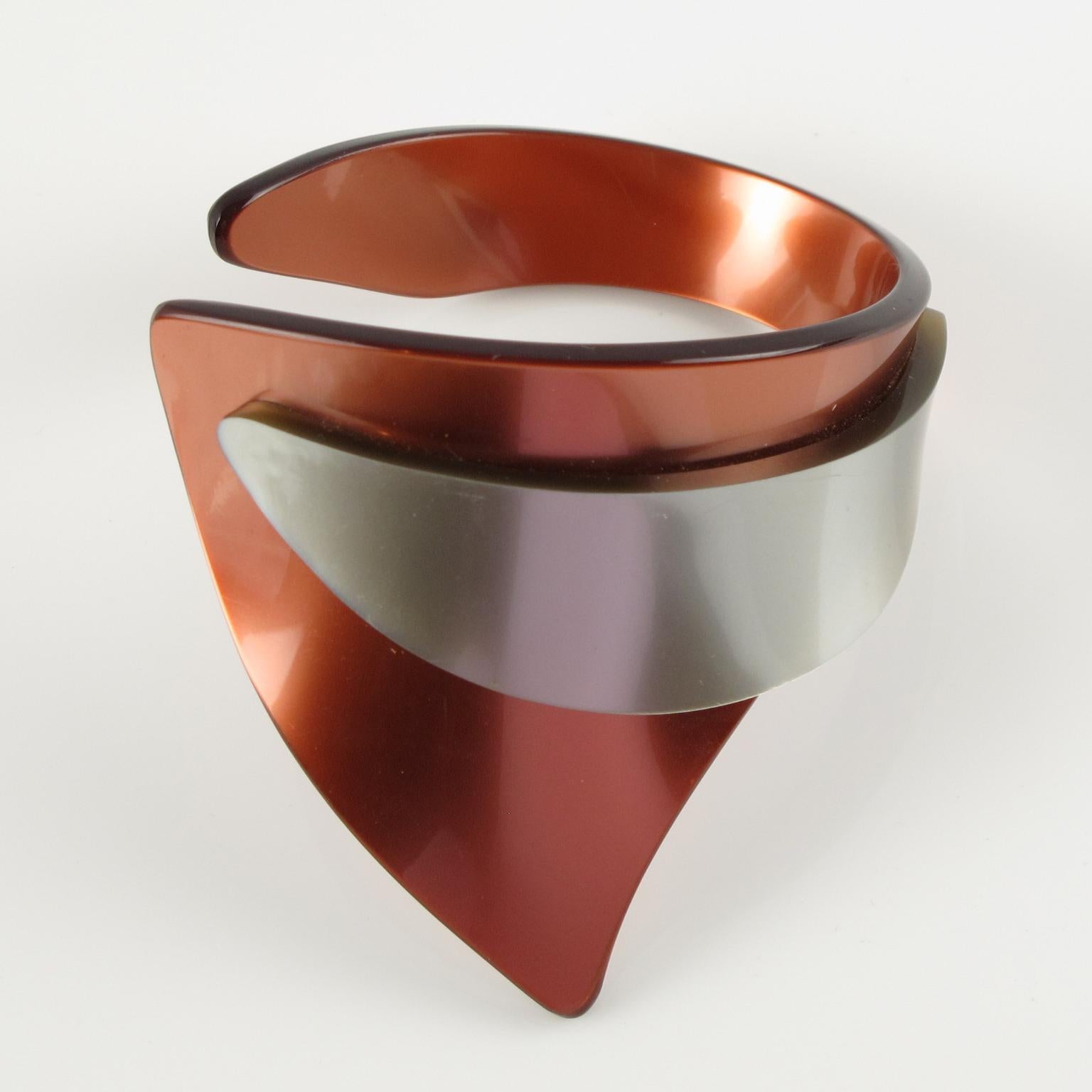 Questo bracciale modernista dello studio artigianale francese Temps Fixes ha un incredibile design futuristico dell'era dello spazio. Il pezzo vanta una forma a bracciale in lucite nei colori grigio e zucca perlata, composta da elementi geometrici