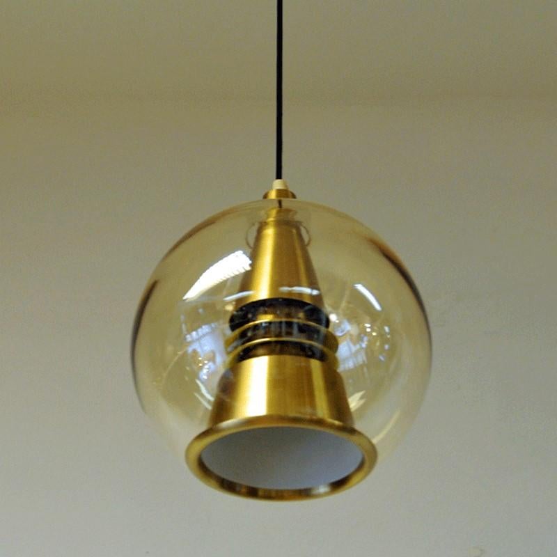 A Space Age inspired ceiling lamp with an amber glass globe shade from the 1960s. Manufactured by T. Røste & Co. Norway. Gives a very nice and calming shine in darker rooms. Copper-plated aluminum reflector. Inside the glassdome. The lamps is