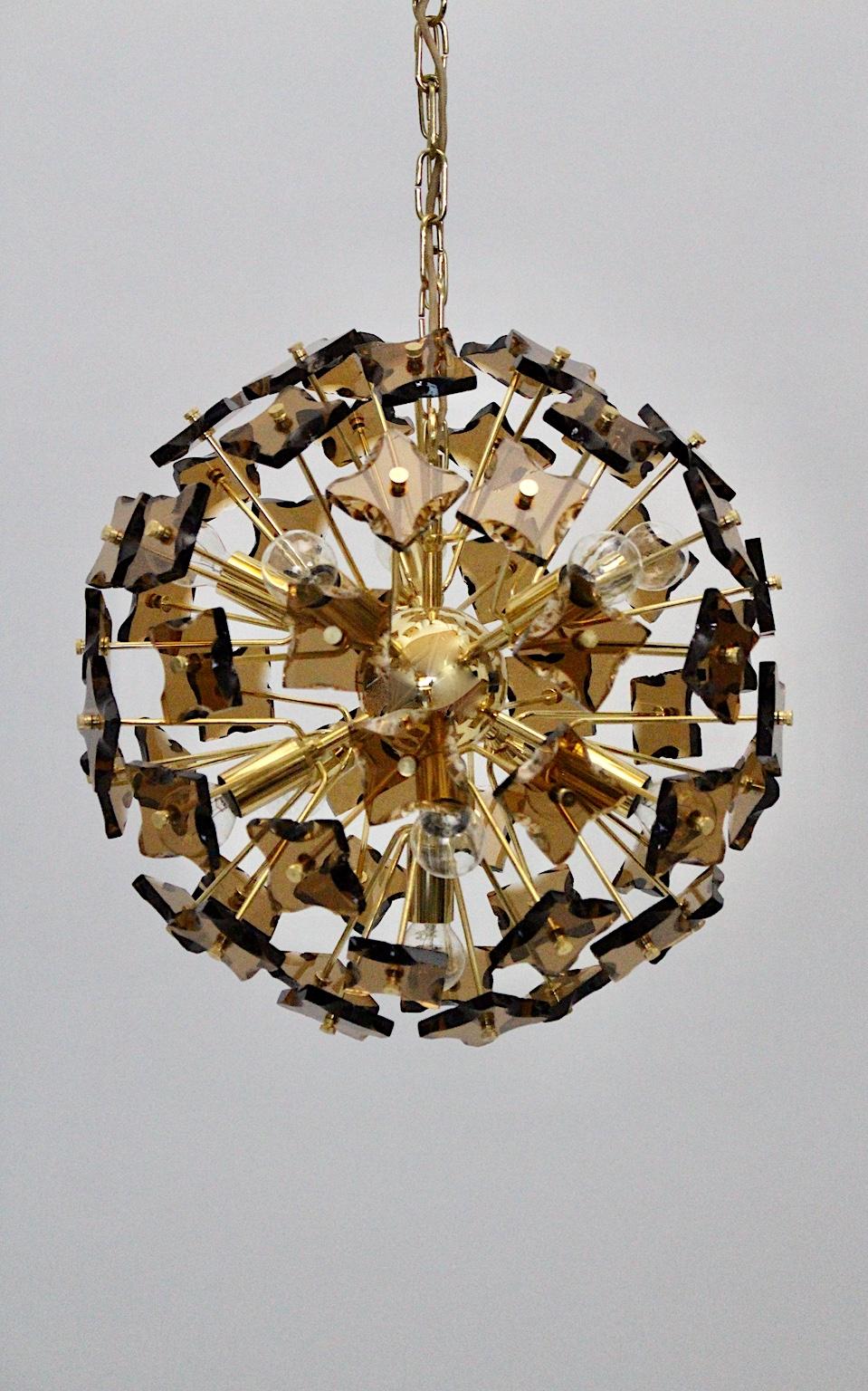A Space Age golden vintage glass Sputnik chandelier or pendant, which was designed in the style of Fontana Arte, 1960s, Italy.
The chandelier features many smoked glass slides with golden-plated brass details.
Eleven E 14 sockets provides
