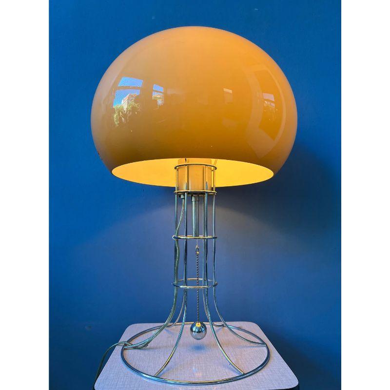 Herda's most famous, big mushroom table lamp. The lamp consists of a mocca-coloured mushroom shade and has a beautiful skeleton-like chrome frame. The lamp has a chrome cord in the middle of the base that allows you to switch the light on and off.