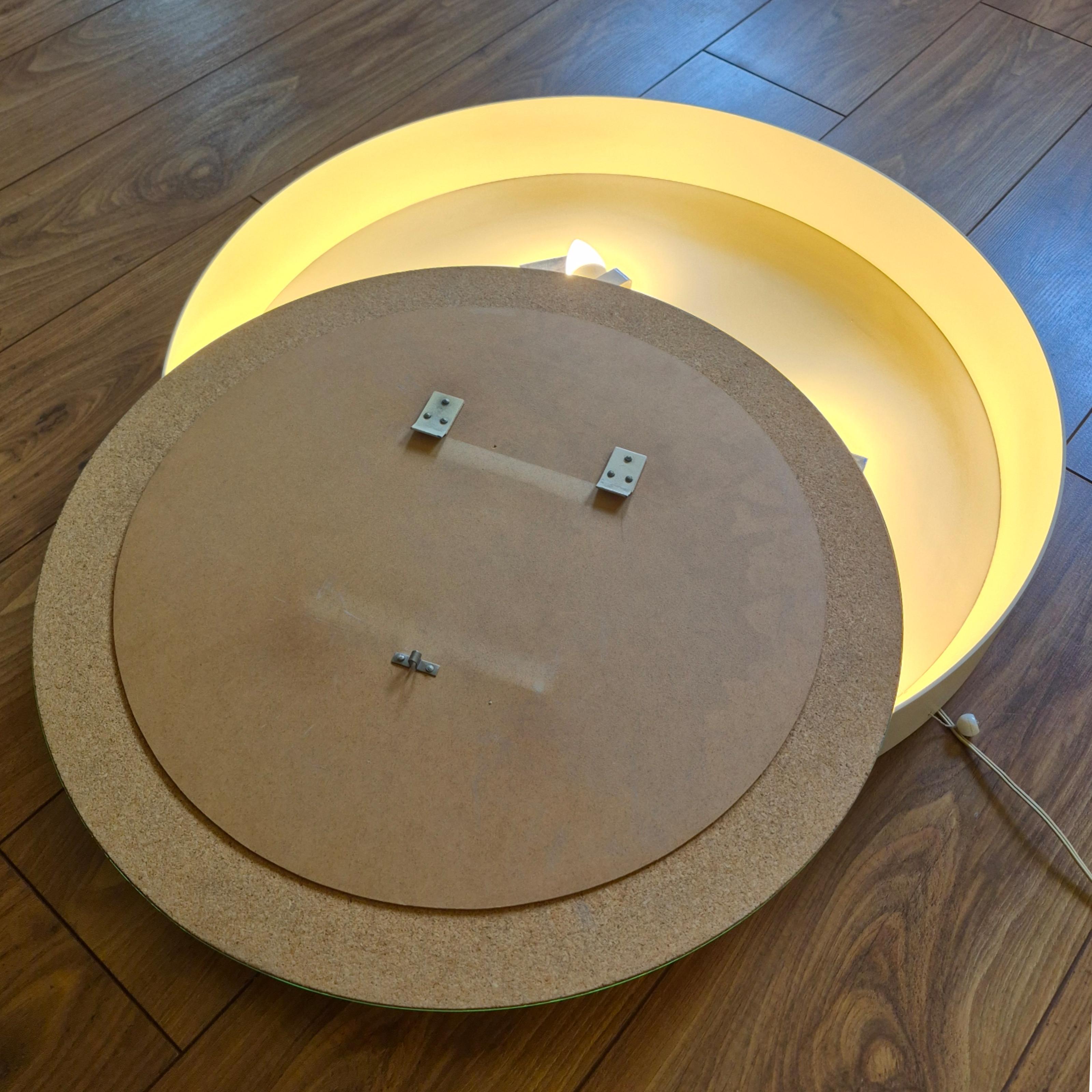 Miroir mural rond fabriqué par Flabeg Allemagne. Le cadre a un bord en bois avec une couche de laque blanche. Eclairage par 4 ampoules derrière le miroir. Actionné par un interrupteur à tirette. 

Il peut être raccordé directement à une boîte de