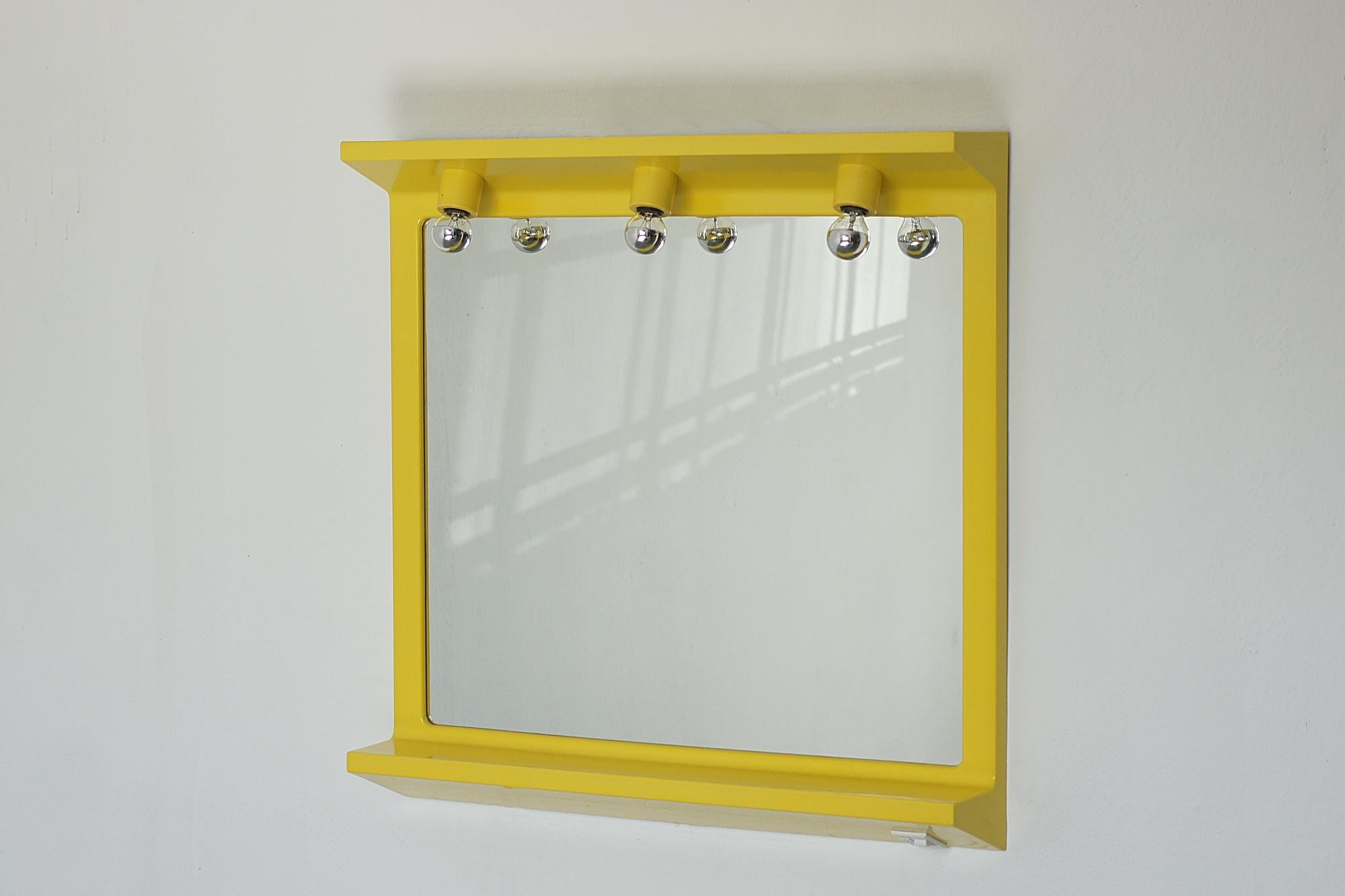 An impressive mirror from the 1980s, designed in Italy in the space age aesthetic. The frame is made of yellow plastic, which, when illuminated, takes on a warm, luminous glow, emphasizing the futuristic character of the object.

Three light bulbs