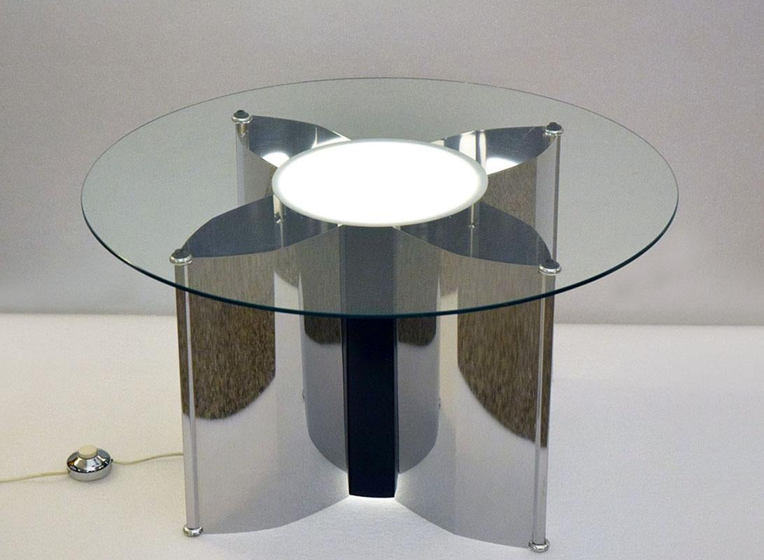 Table basse avec éclairage, fabrication italienne des années 1970.  Cadre en acier poli en forme d'étoile avec lumière centrale et quatre lumières latérales avec diffuseurs en plexiglas, dessus en cristal rond. 
En parfait état.