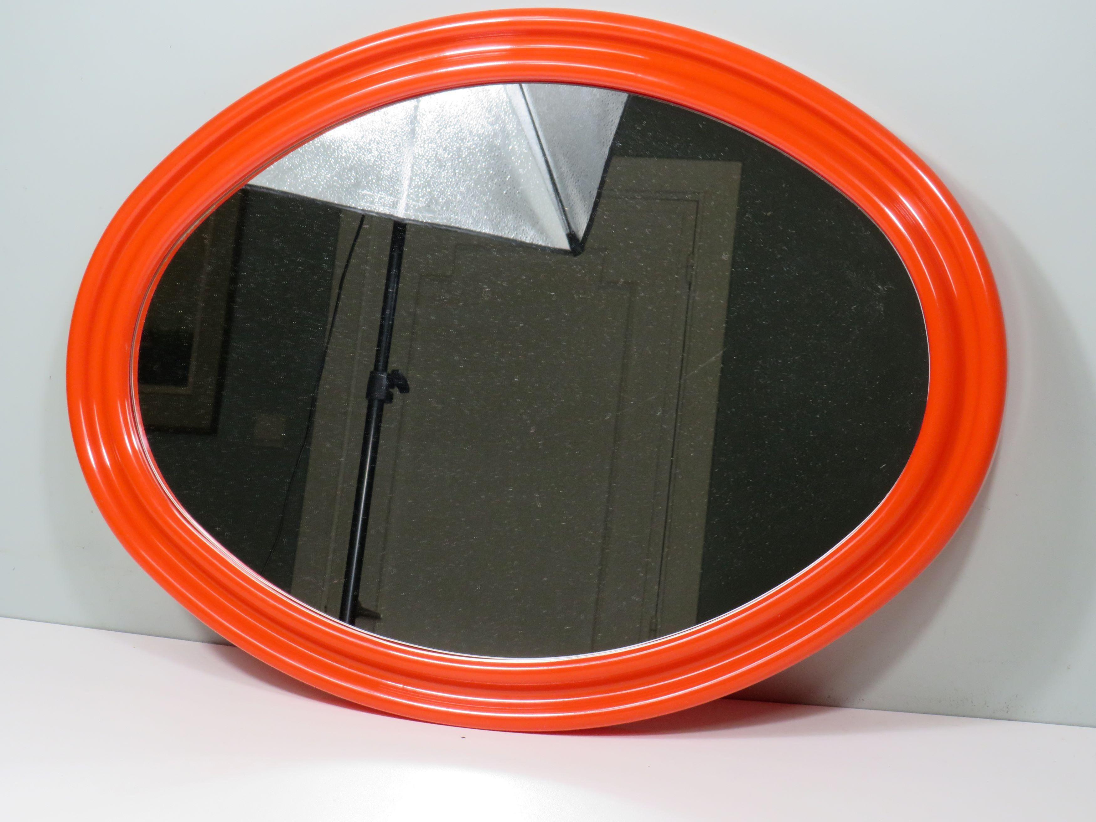 Large oval Space Age/Pop Art mirror in the style of Guzzini and Verner Panton.
The mirror glass is inlaid in the molded plastic shape with an intense orange color and the back has 2 mounting holes so that the mirror can be hung both horizontally and