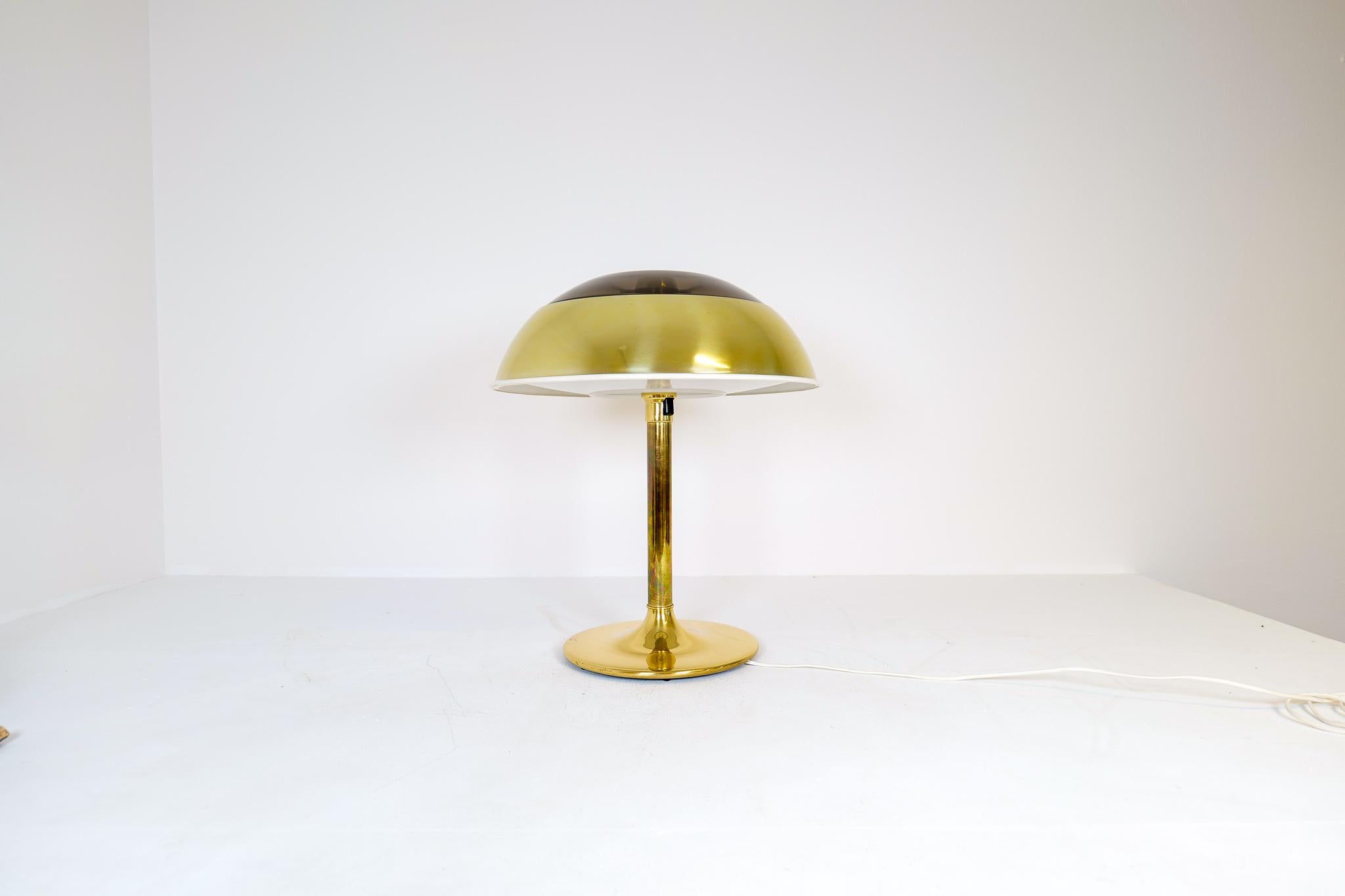 This large space age table lamp in brass was manufactured at Fagerhults Belysning in Sweden, 1970s.
The shade is in brass metal and plastic, the rest of it in brass. When lit it gives a nice cool light. 

Good working condition, scratches on the