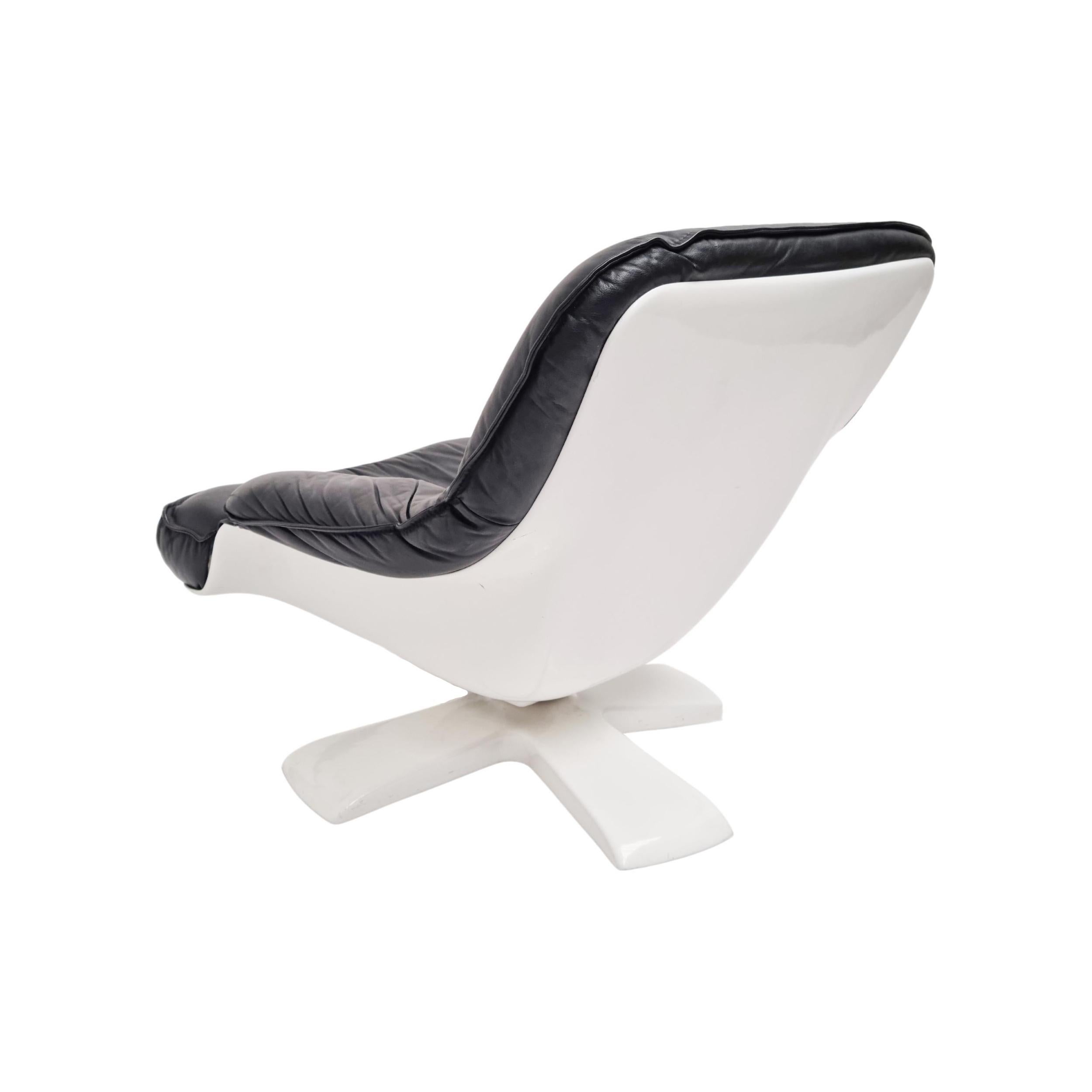 Organic shaped lounge chair.  This chair consists of a molded fiberglass shell that is comfortably upholstered in black leather. The thick star-like base provides stability and features a tilt as well as a swivel function to maximize comfort. The