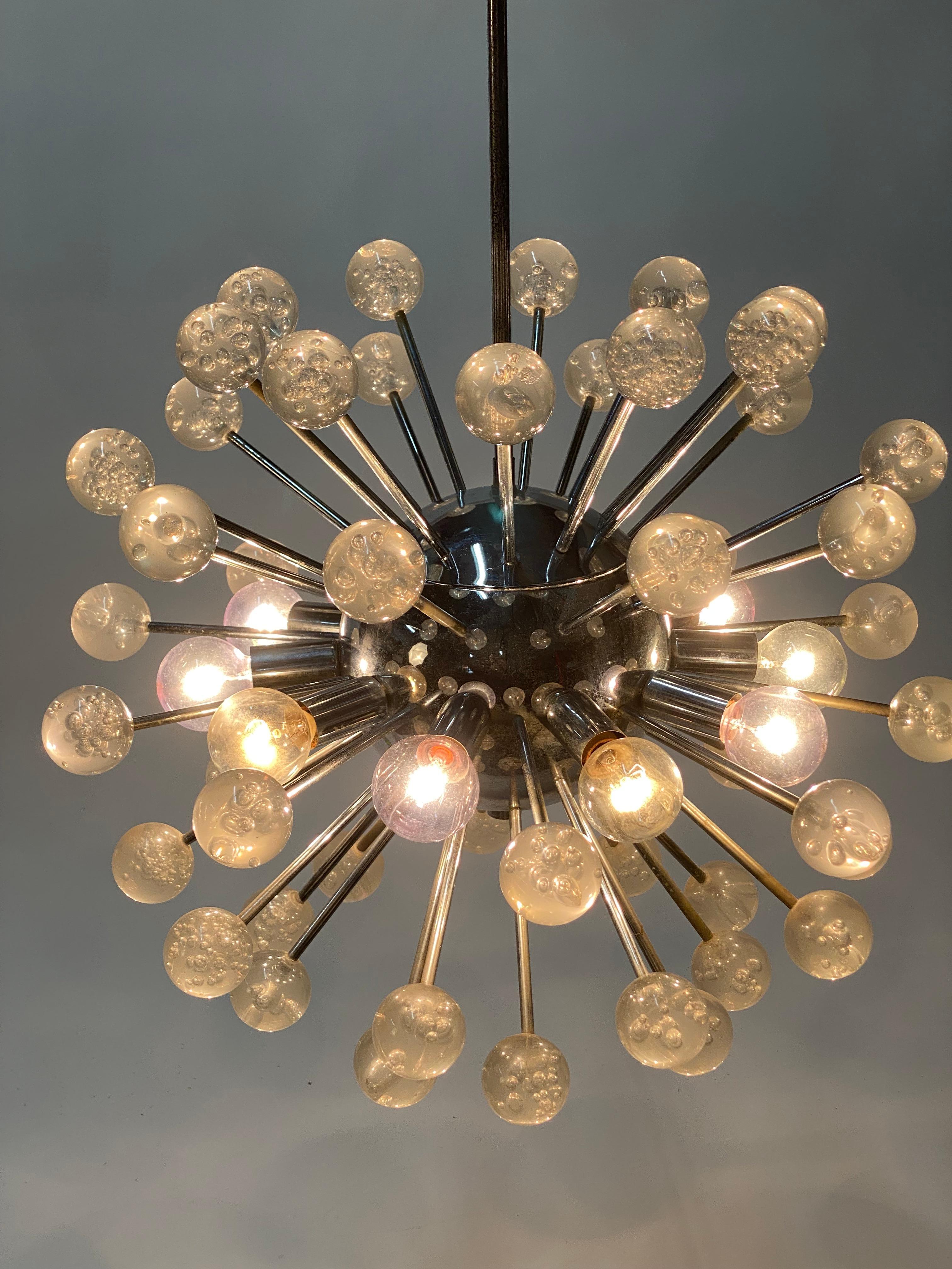 Chrome and Lucite space age chandelier. Circa late 1960s-70s. A chrome plated sphere with outreaching arms that end in bubble filled lucite balls. The middle portion is adorned with light bulbs. The lucite balls do not light up. A light fixture that