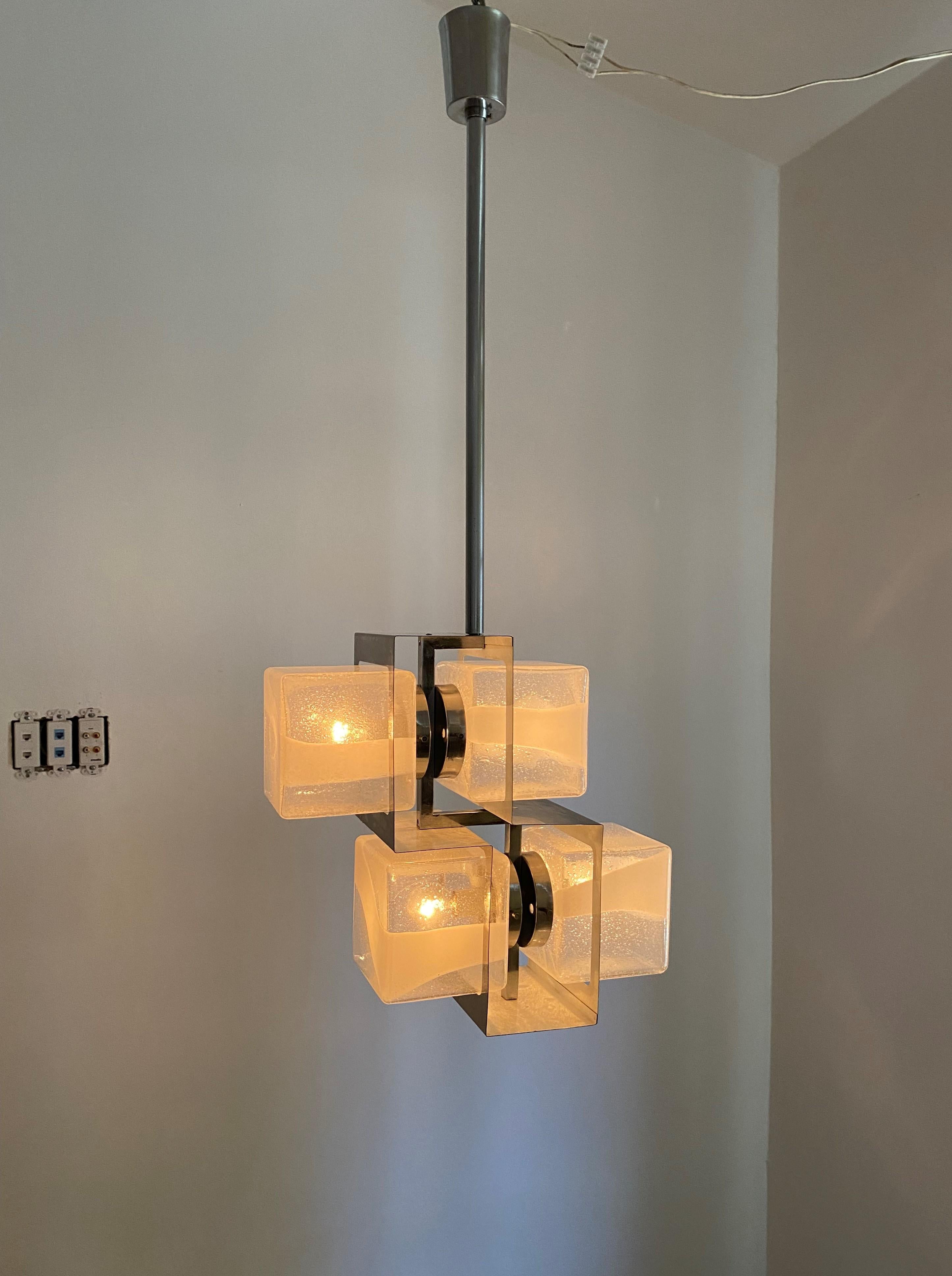 Lampadario Mid-Century Modern in hardware cromato e vetro di Murano soffiato a mano di Mazzega, con vetro di Carlo Nason, Murano, Italia, circa 1970.
Il lampadario da solo misura 40 cm di altezza (senza l'asta di metallo e il baldacchino).