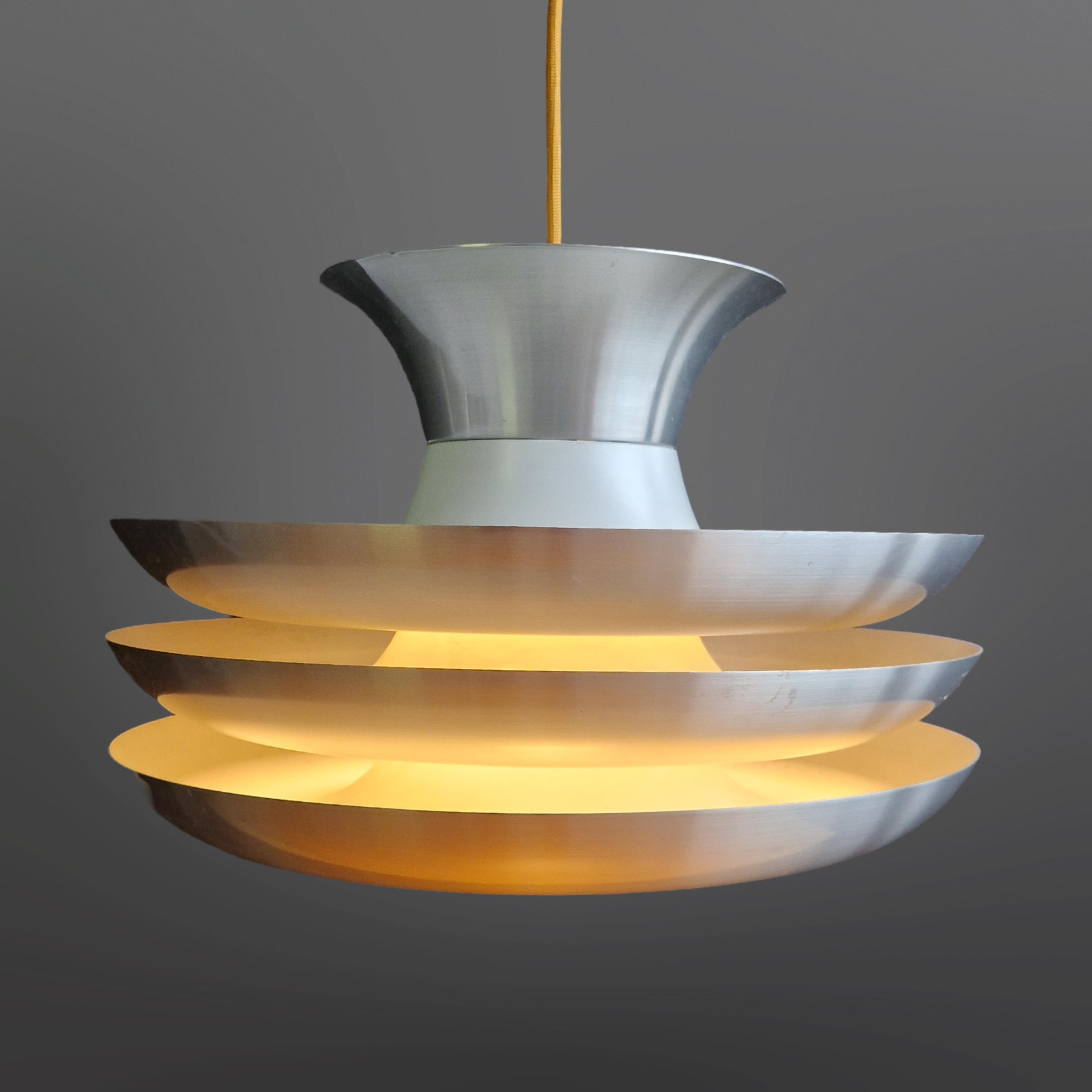 Stacked saucers pendant lamp. Made in the Netherlands in the 1960s. Made from aluminium. It has one central plug that holds a standard e27 bulb. Directional light from the centre and diffused light from the light that shines through the layers. 
The