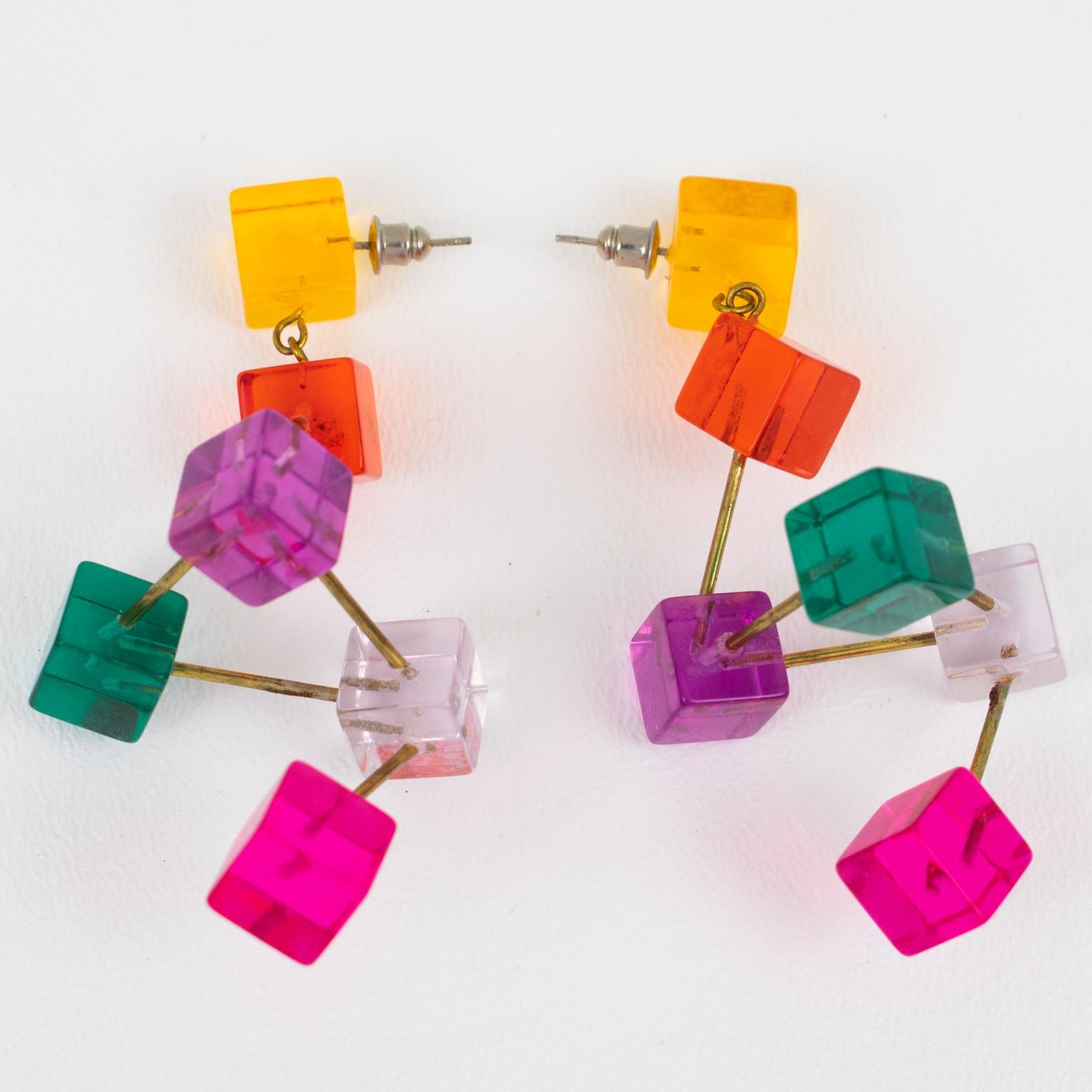 Diese atemberaubenden, baumelnden Lucite-Ohrringe aus den 1960er Jahren zeigen ein dimensionales Space Age-Atomdesign mit mehrfarbigen Würfeln und Metallgliedern. Die Stücke sind in den Farben transparent, orange, rot, lila, pink und grün gehalten.