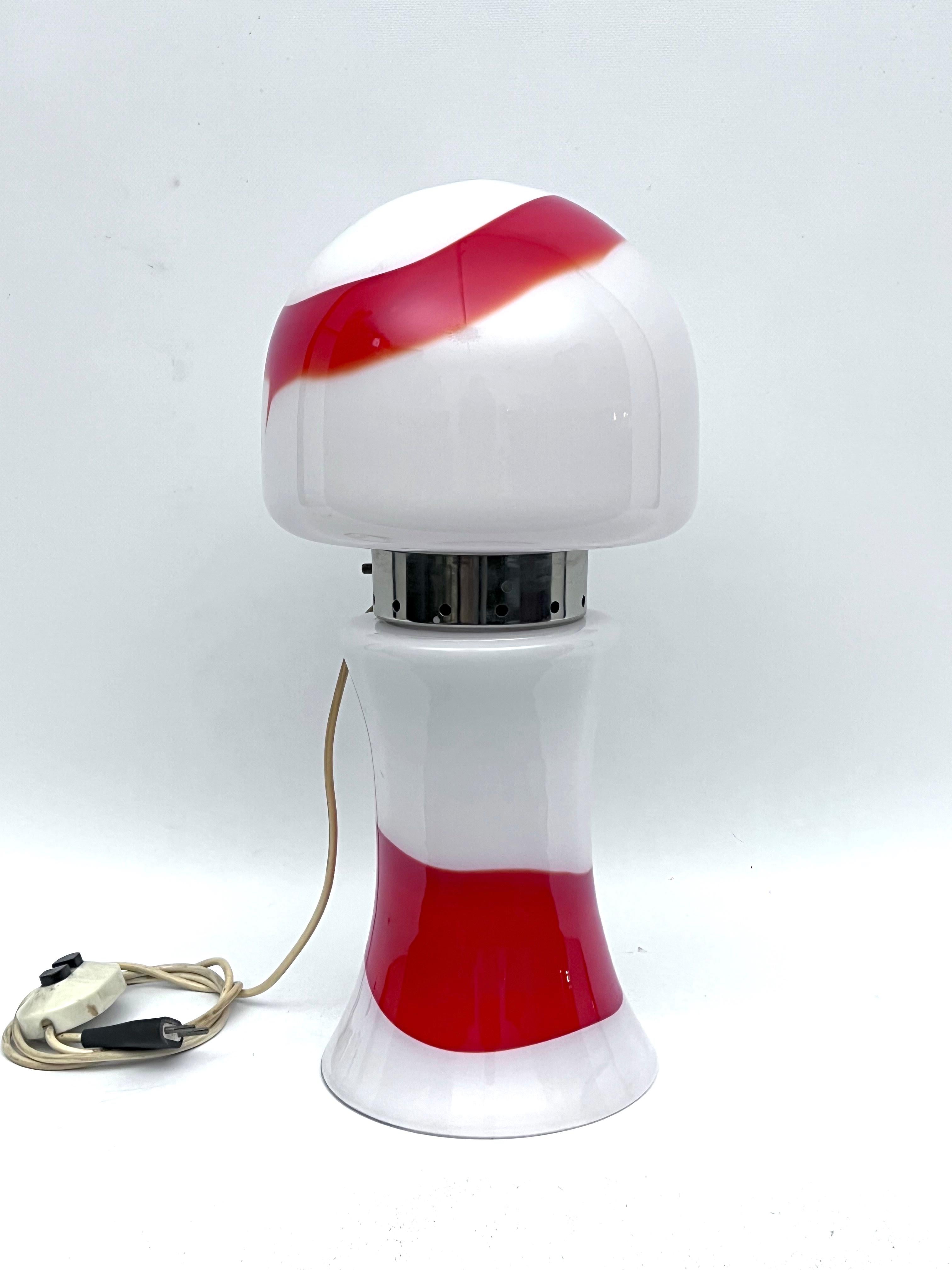 Cette lampe de table en verre de Murano est en excellent état et présente des traces normales d'âge et d'utilisation. Produit en Italie dans les années 70. Fonctionne entièrement avec la norme européenne, adaptable sur demande à la norme américaine.